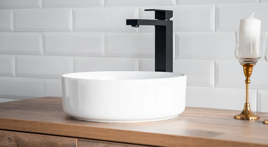 White vessel sink with matte black faucet on wood vanity in a bathroom renovation.