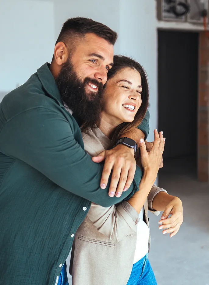 Happy couple embraces in newly renovated home, celebrating completed renovation services.
