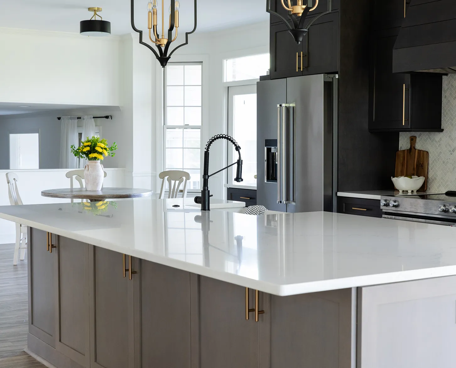 Sleek kitchen remodel with black cabinetry, brass hardware, and white quartz island.