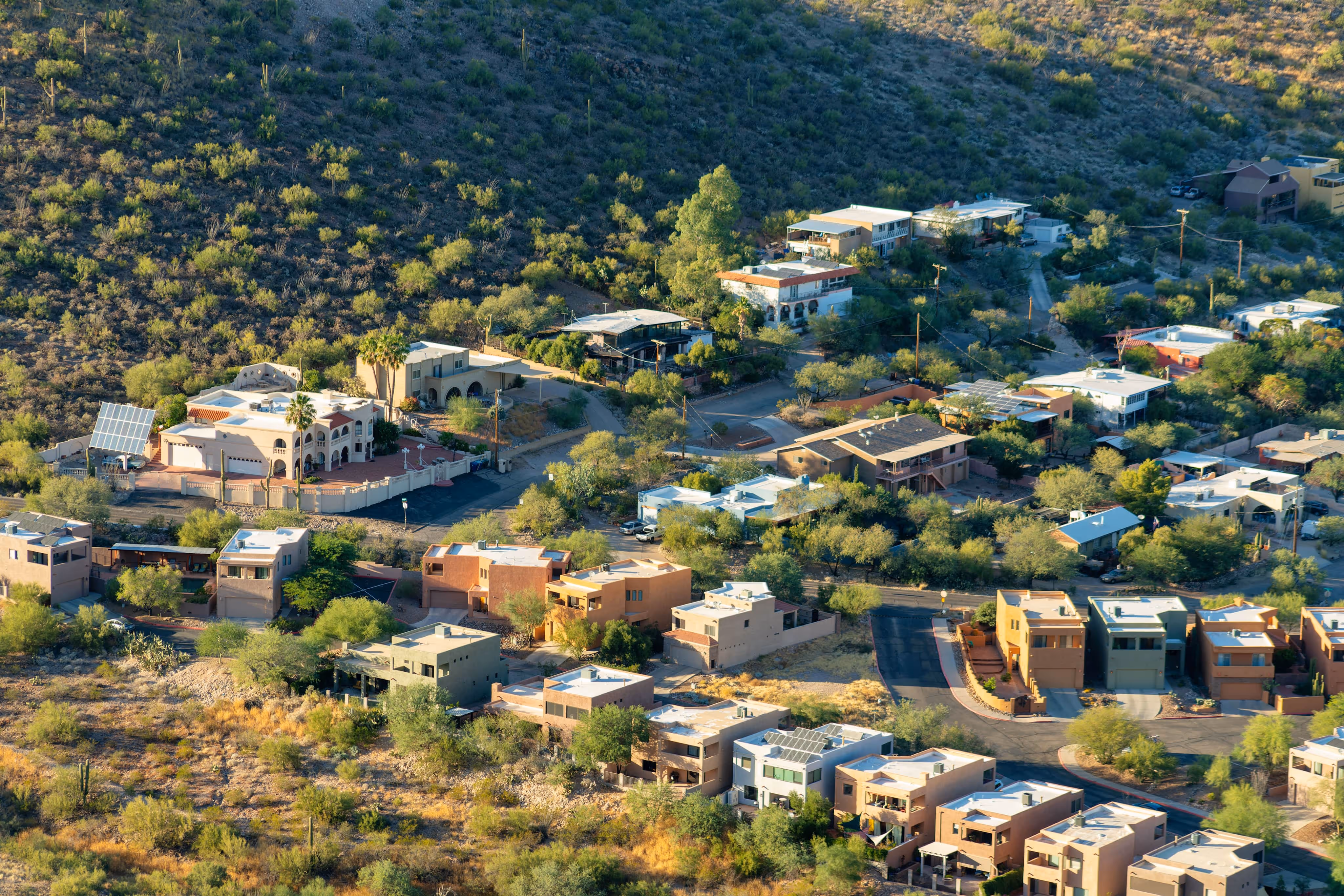 Overhead perspective of a desert town with various houses surrounded by sandy terrain and sparse vegetation.
