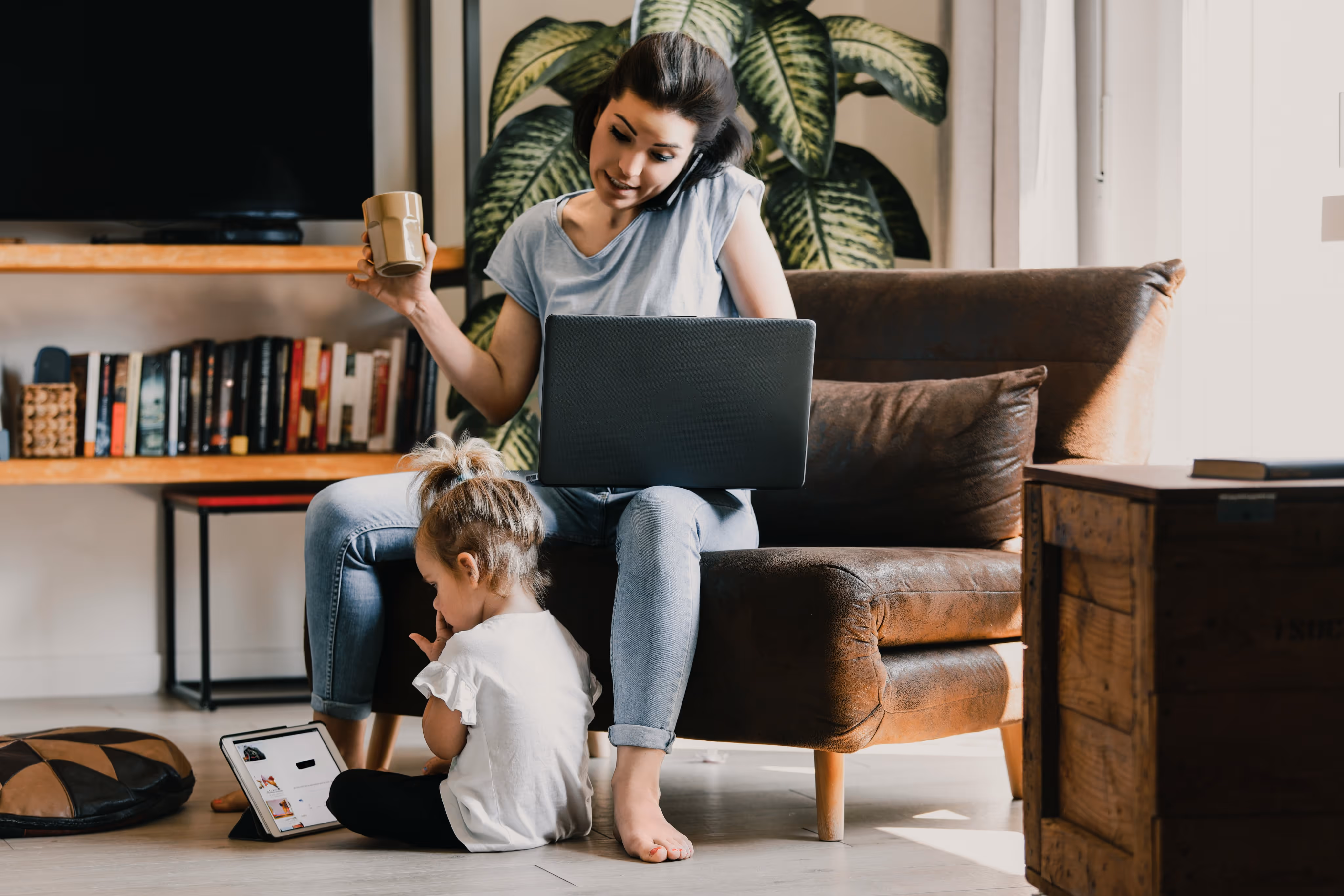 A woman and child sit together on a couch, using a laptop for a shared activity.