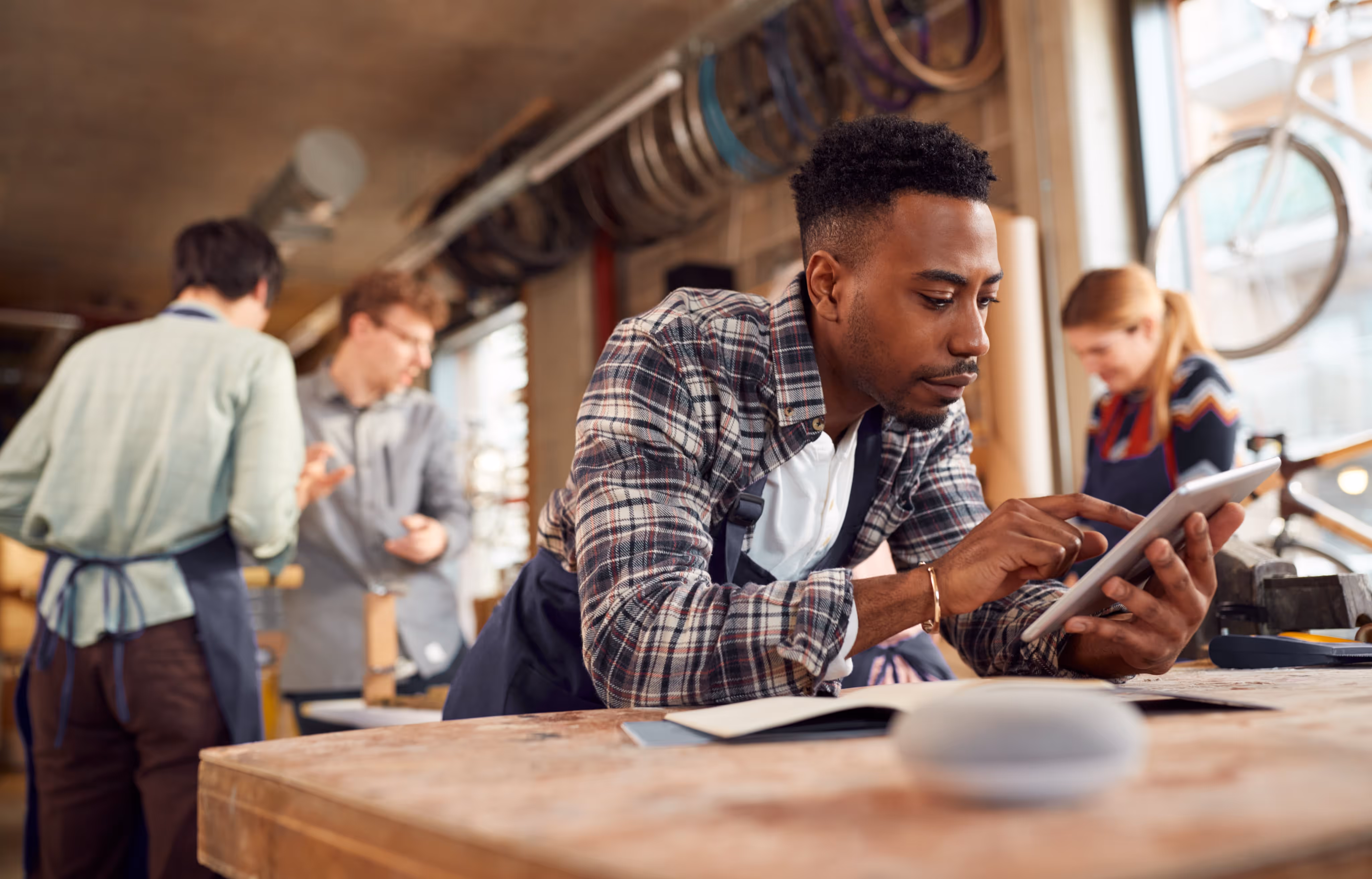 A man in an apron is focused on using a tablet, likely engaged in a cooking or food-related task.