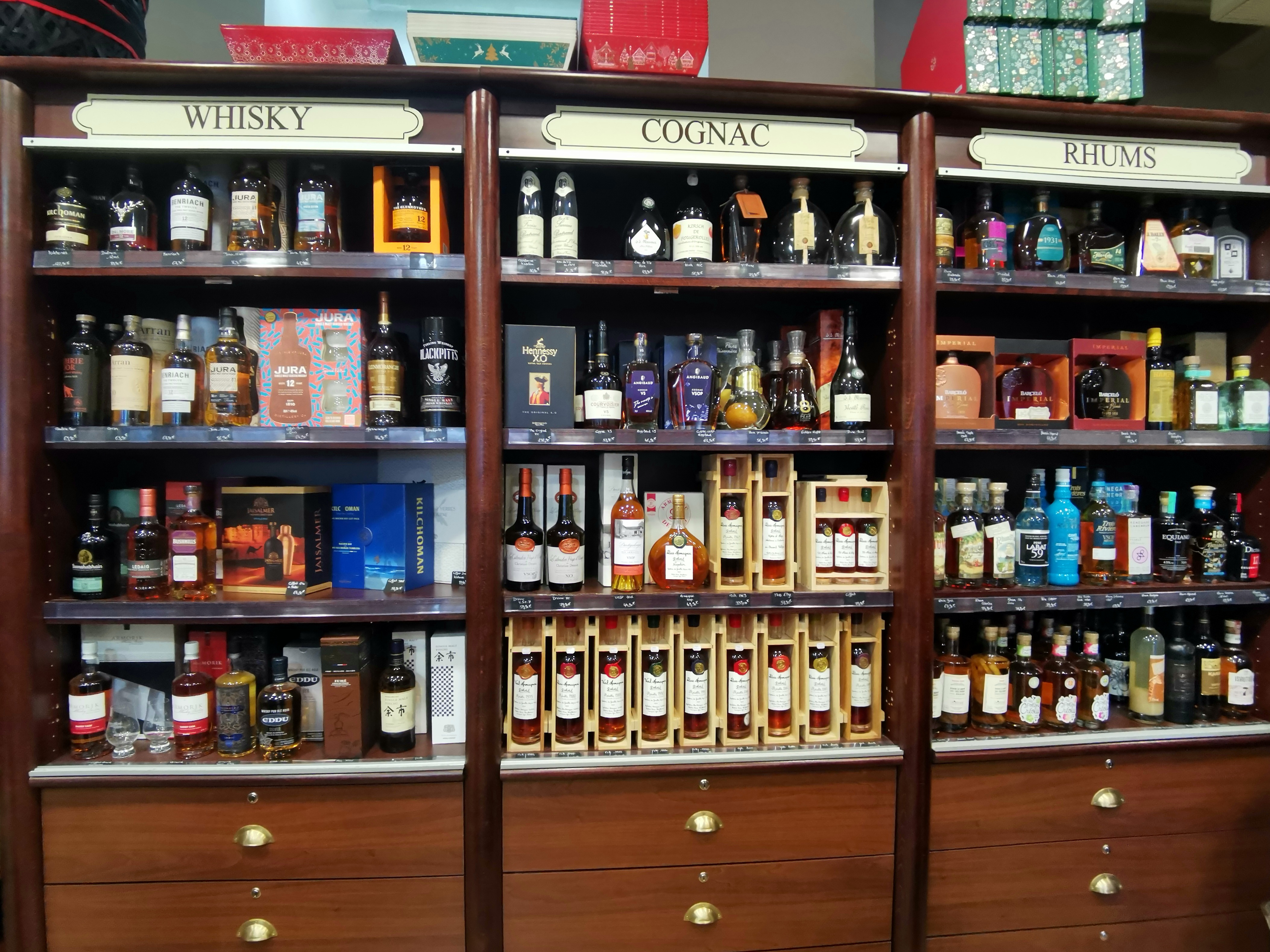 Des étagères présentent des bouteilles de whisky, de cognac et de rhum dans la boutique Maison Lhôte à Tours.
