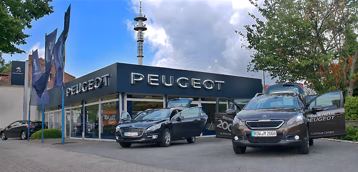 Fahrzeugempfangsbereich bei Peugeot mit zwei weißen Barhockern vor einem Empfangstresen und einem geparkten schwarzen E-Roller.