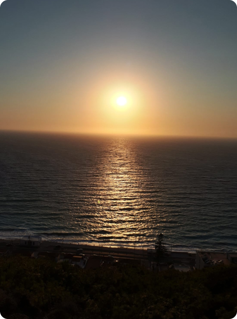 Sonnenuntergang über dem Meer mit reflektierendem Sonnenlicht auf den Wellen und dunklem Vordergrund.