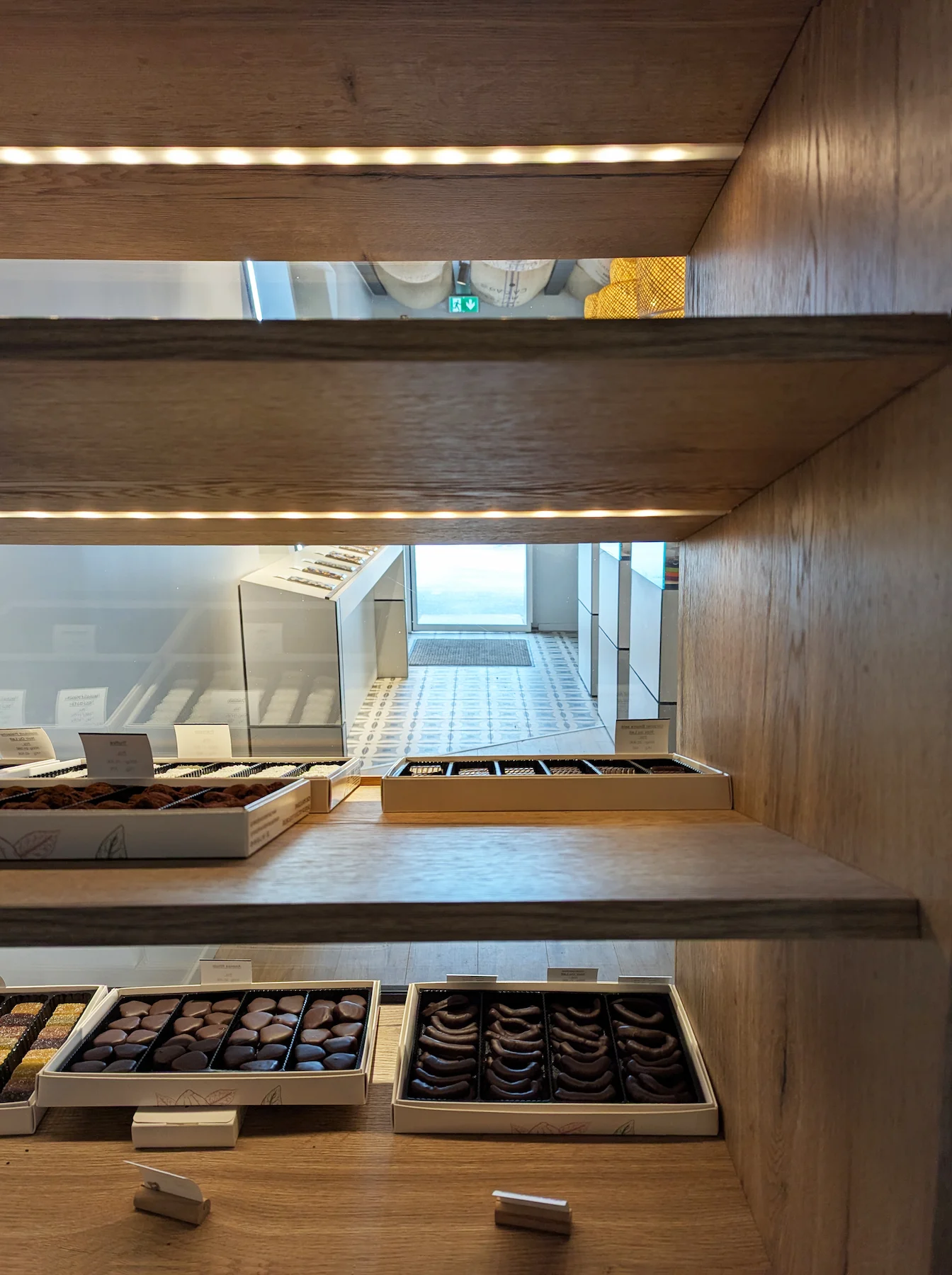 Étagères en bois intégrées présentant des chocolats, visibles dans l’aménagement intérieur de Valentine pour la chocolaterie Val Janon.
