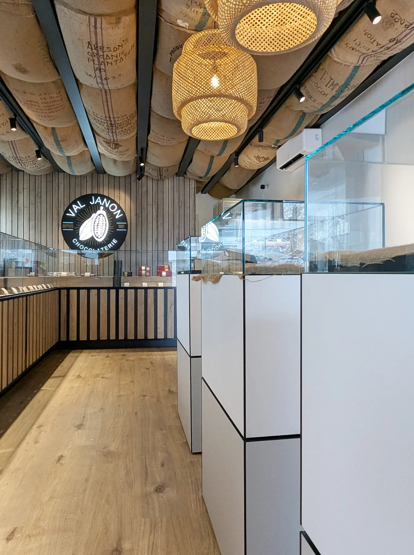 Allée de la boutique montrant les vitrines blanches et le plafond décoré de sacs de jute, dans le design réalisé par Valentine.