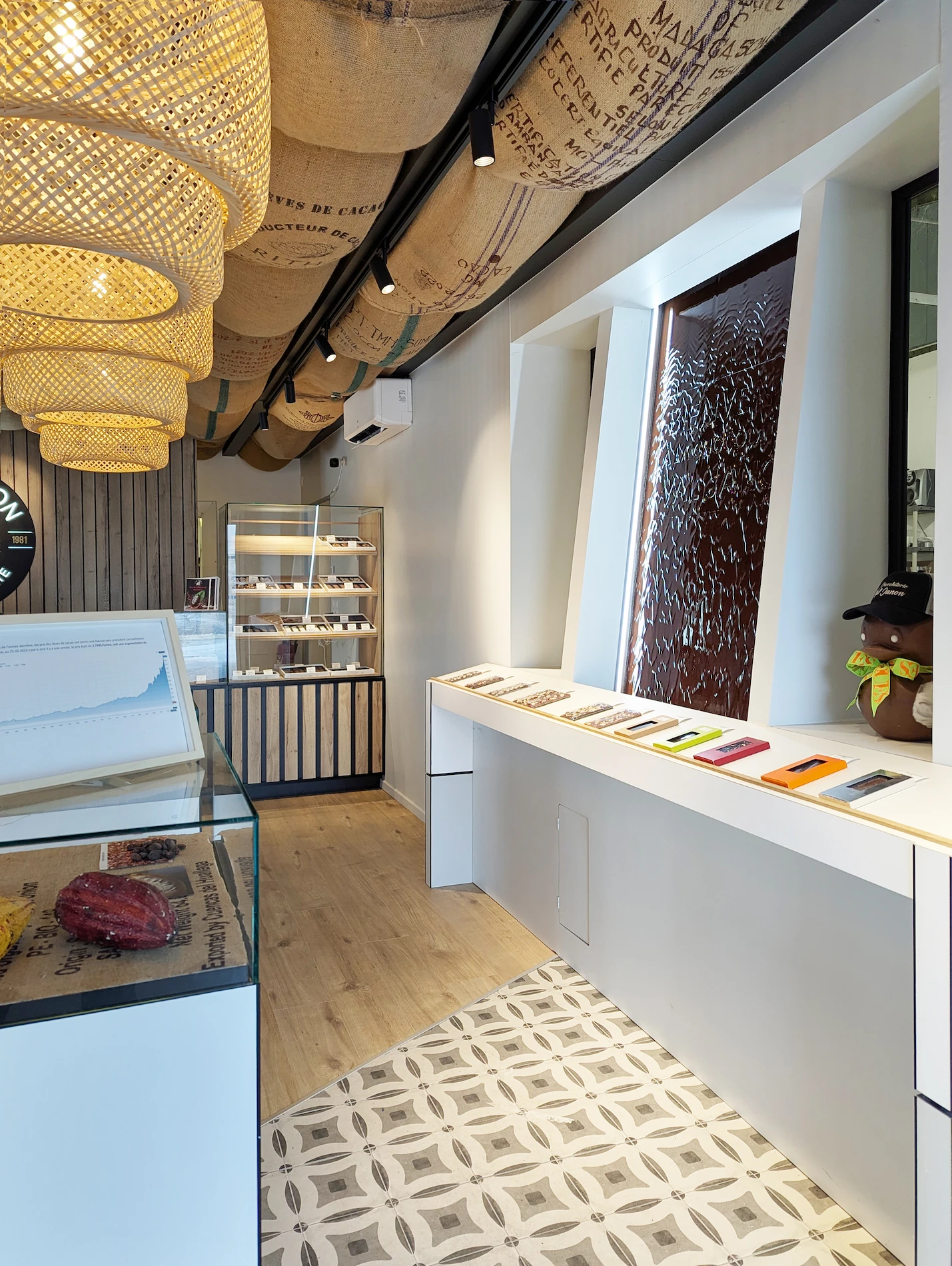 Espace boutique de la chocolaterie Val Janon à Saint-Étienne, conçu par Valentine Bourdier : luminaires en rotin, tablette d’exposition et plafond en sacs de jute