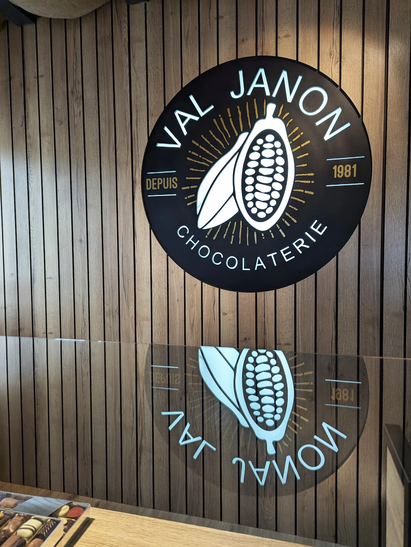Logo circulaire Val Janon reflété dans le comptoir en verre, dans l’aménagement intérieur réalisé par Valentine 