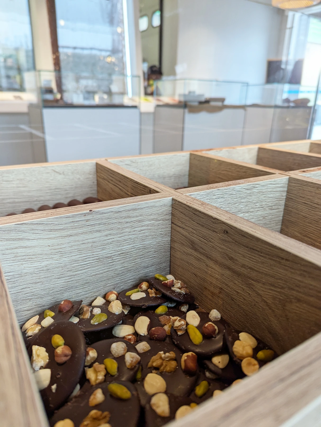 Présentoir en bois rempli de chocolats aux fruits secs, partie du design intérieur imaginé par l'agence Jiwa.A pour la chocolaterie Val Janon