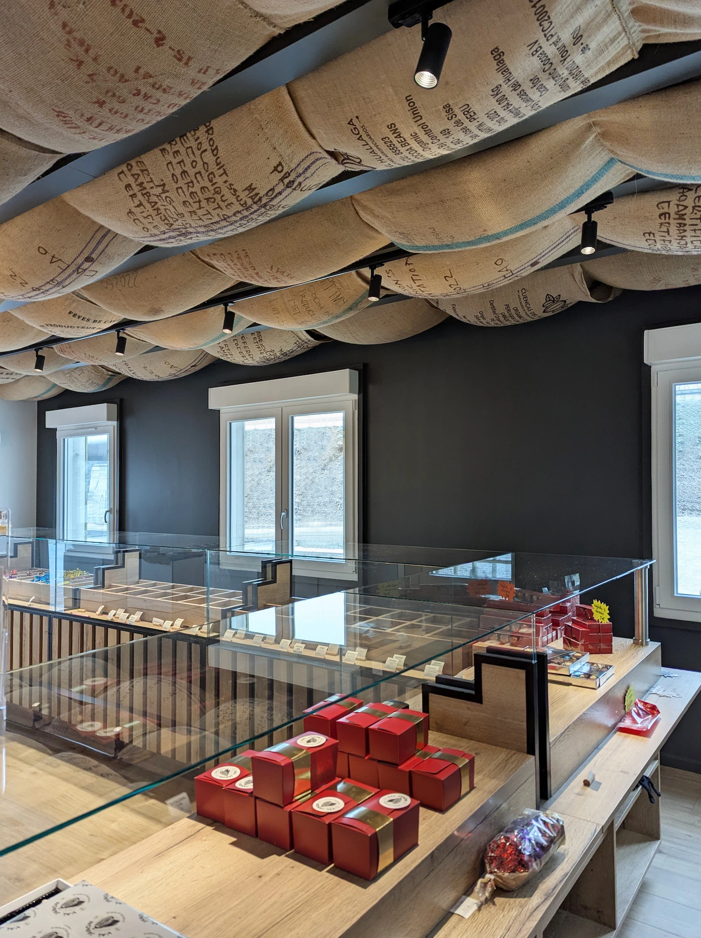 Vue du magasin Val Janon : plafond en sacs de jute suspendus, vitrines en verre et mobilier bois
