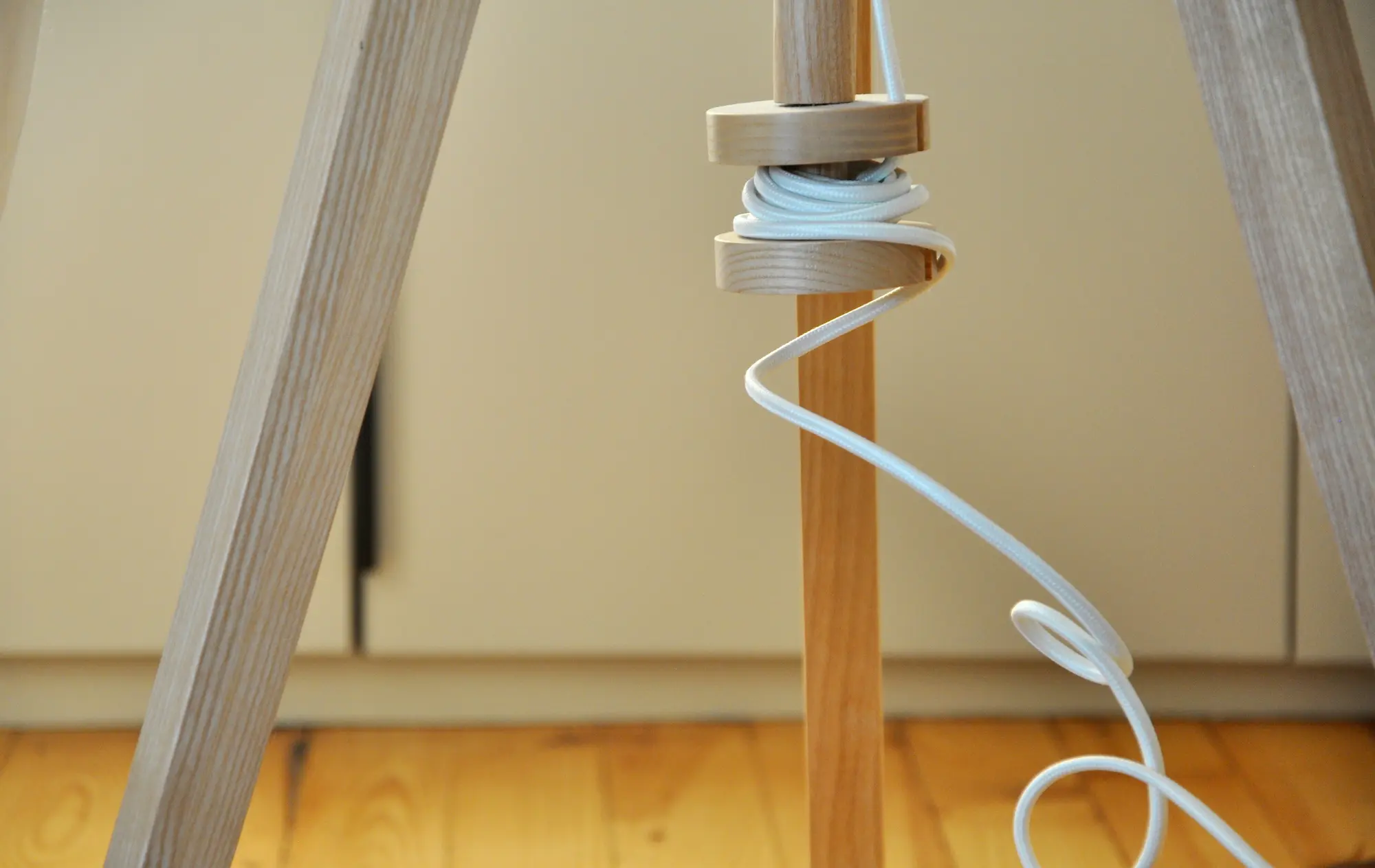 Gros plan sur un pied de lampe en bois au design minimaliste.