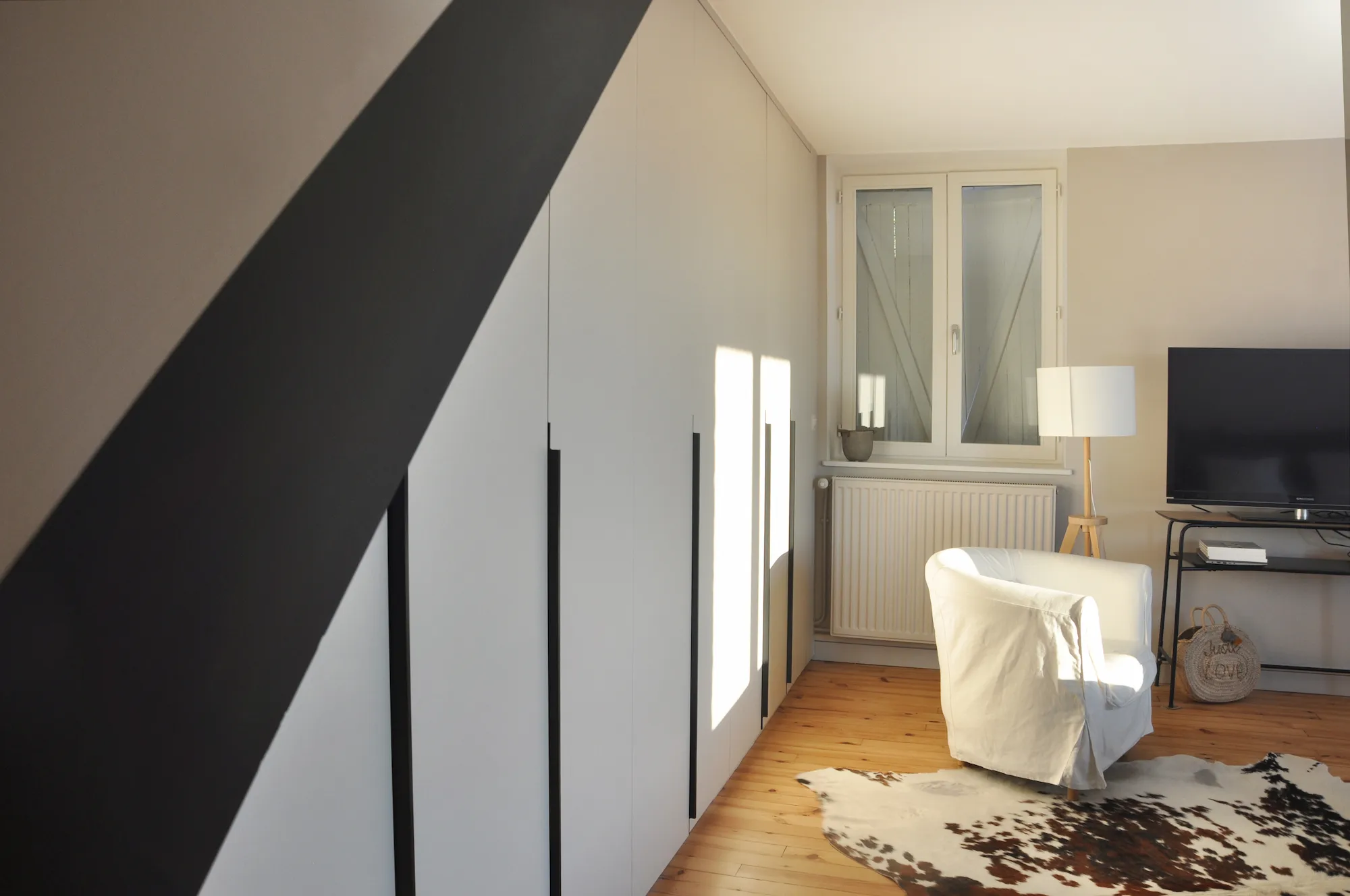 Rangement sur-mesure installé sous pente, optimisant l’espace de la chambre.
