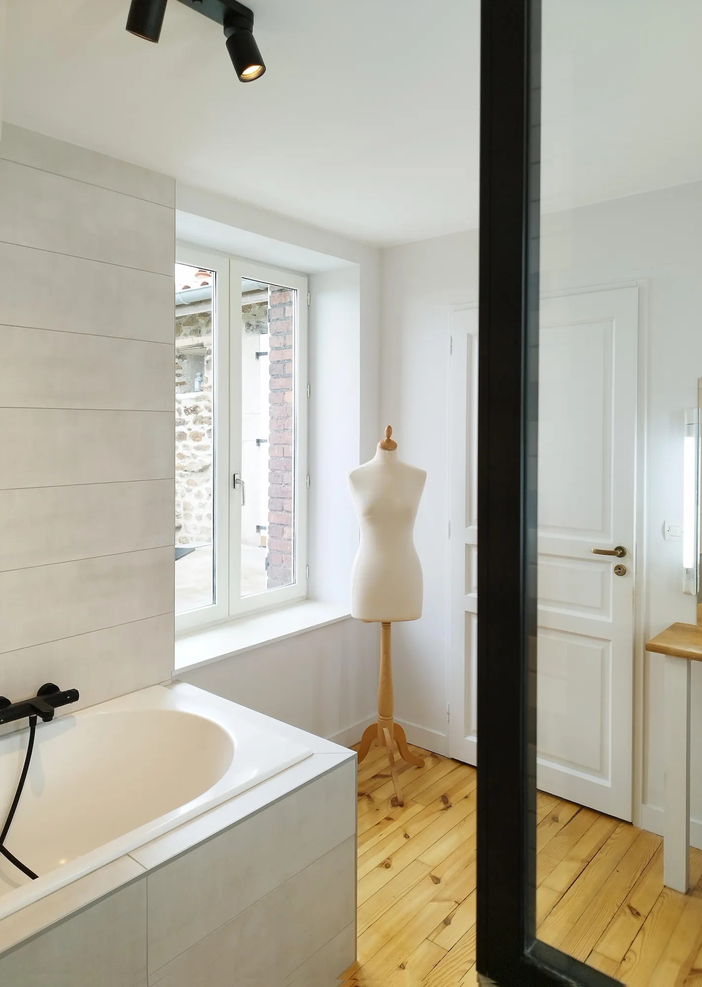 Suite parentale avec baignoire épurée, parquet chaleureux et détails décoratifs.