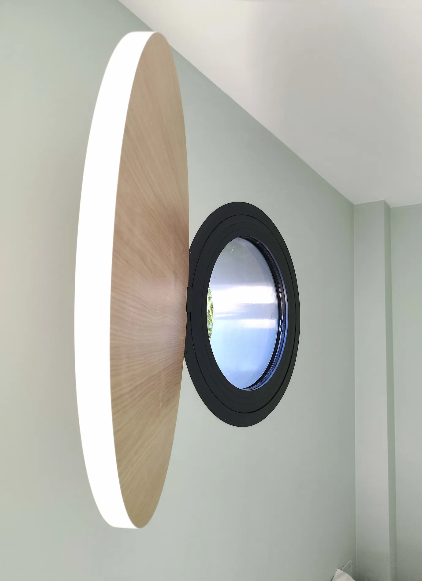 Fenêtre ronde intégrée dans la chambre d’une extension résidentielle.