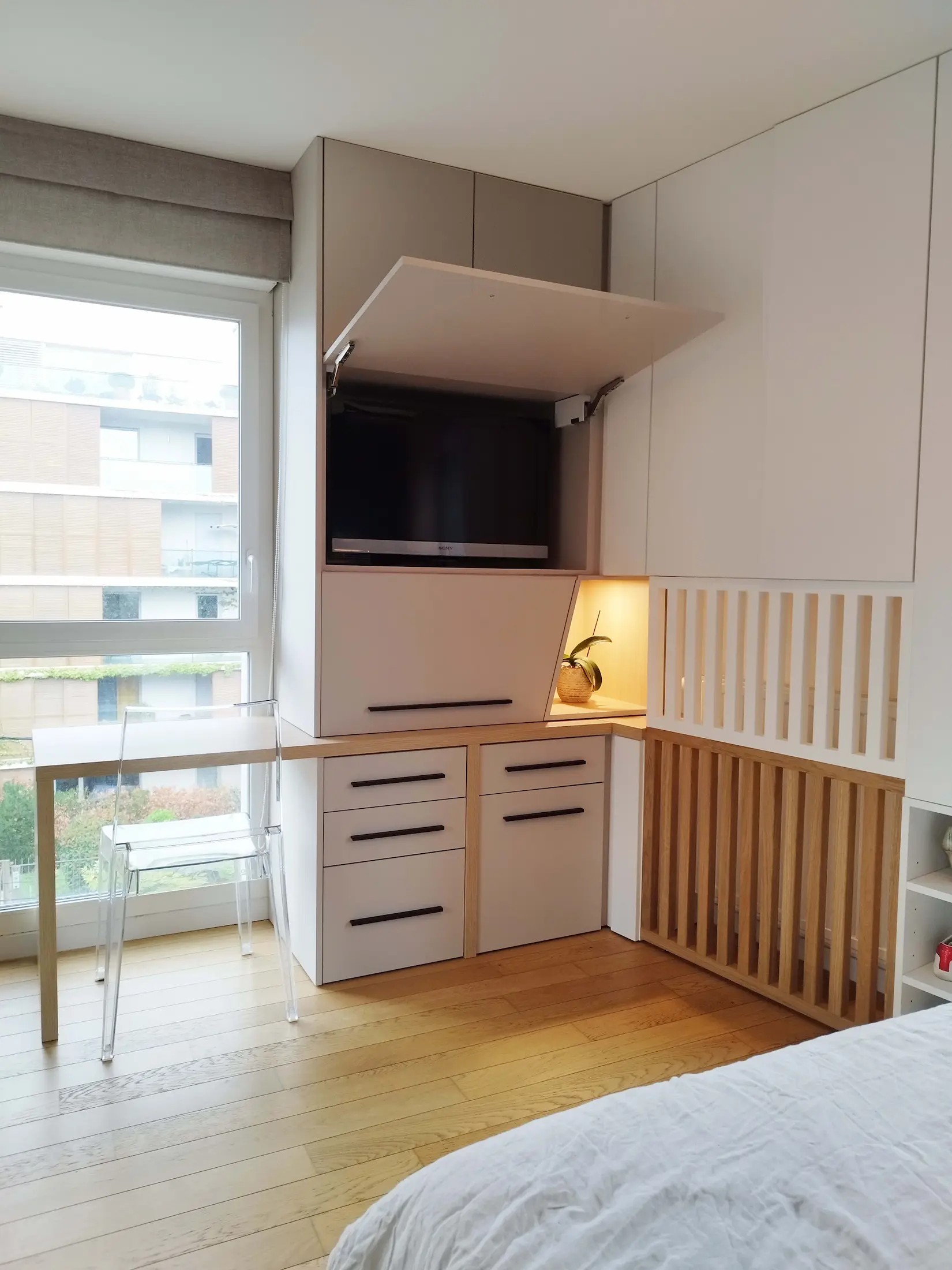 Partie TV intégrée dans le meuble sur mesure, pensée pour rester discrète dans la chambre.