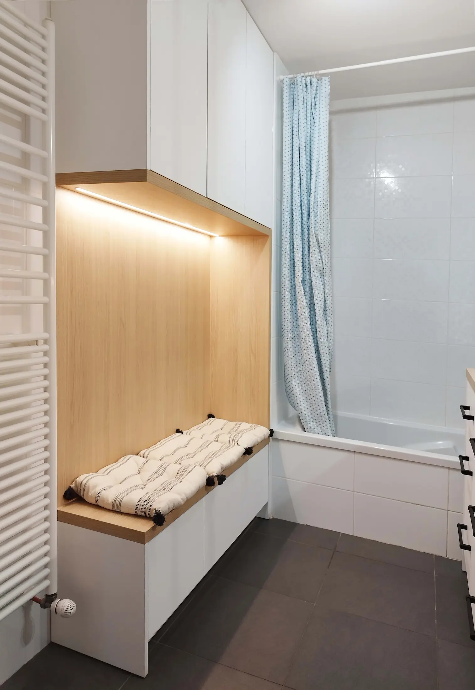 Assise intégrée et rangements muraux créés par Jiwa.A dans la salle de bain.