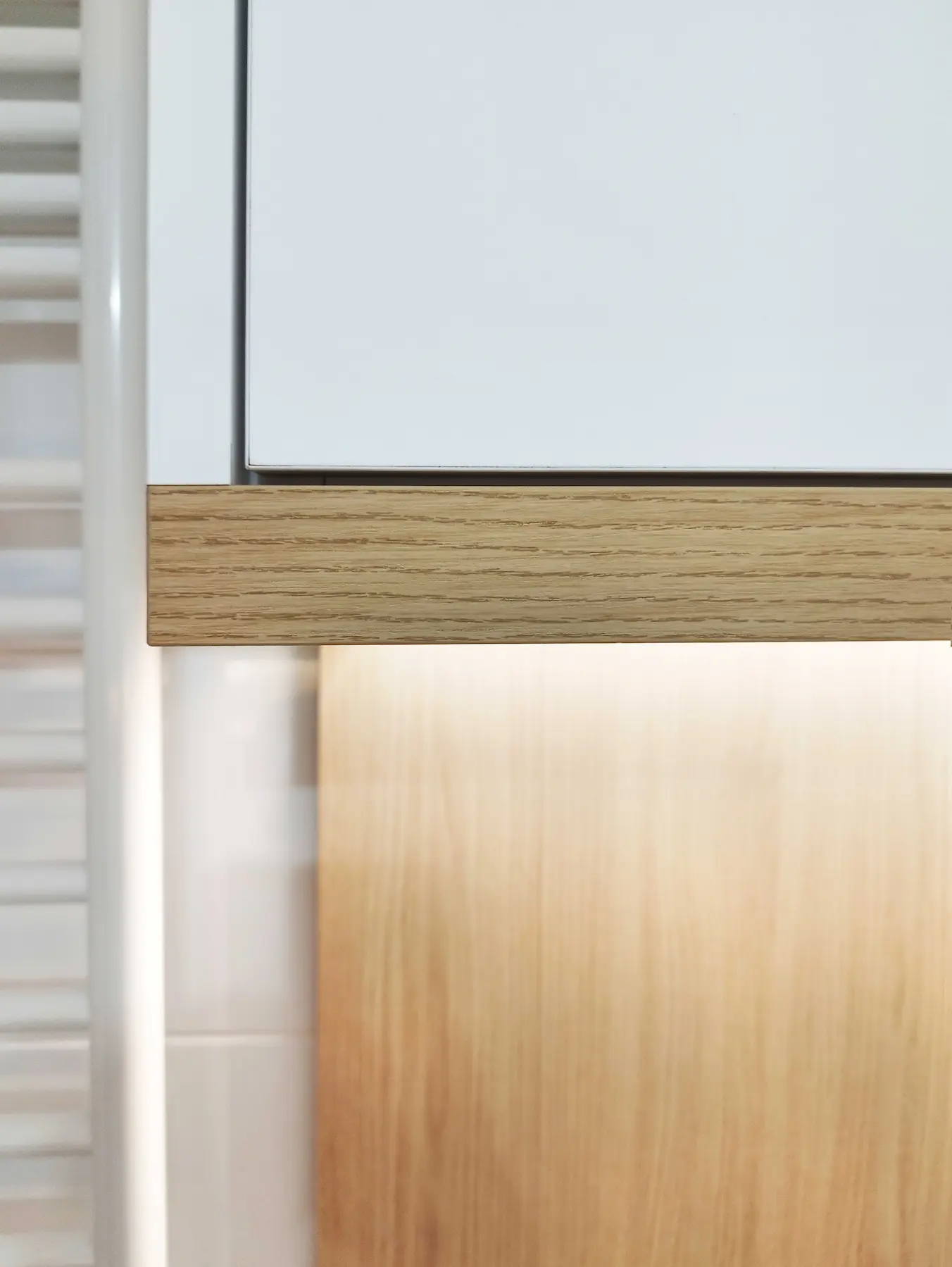 Détail du bandeau en bois et du meuble haut réalisé sur mesure par Jiwaa dans la salle de bain.