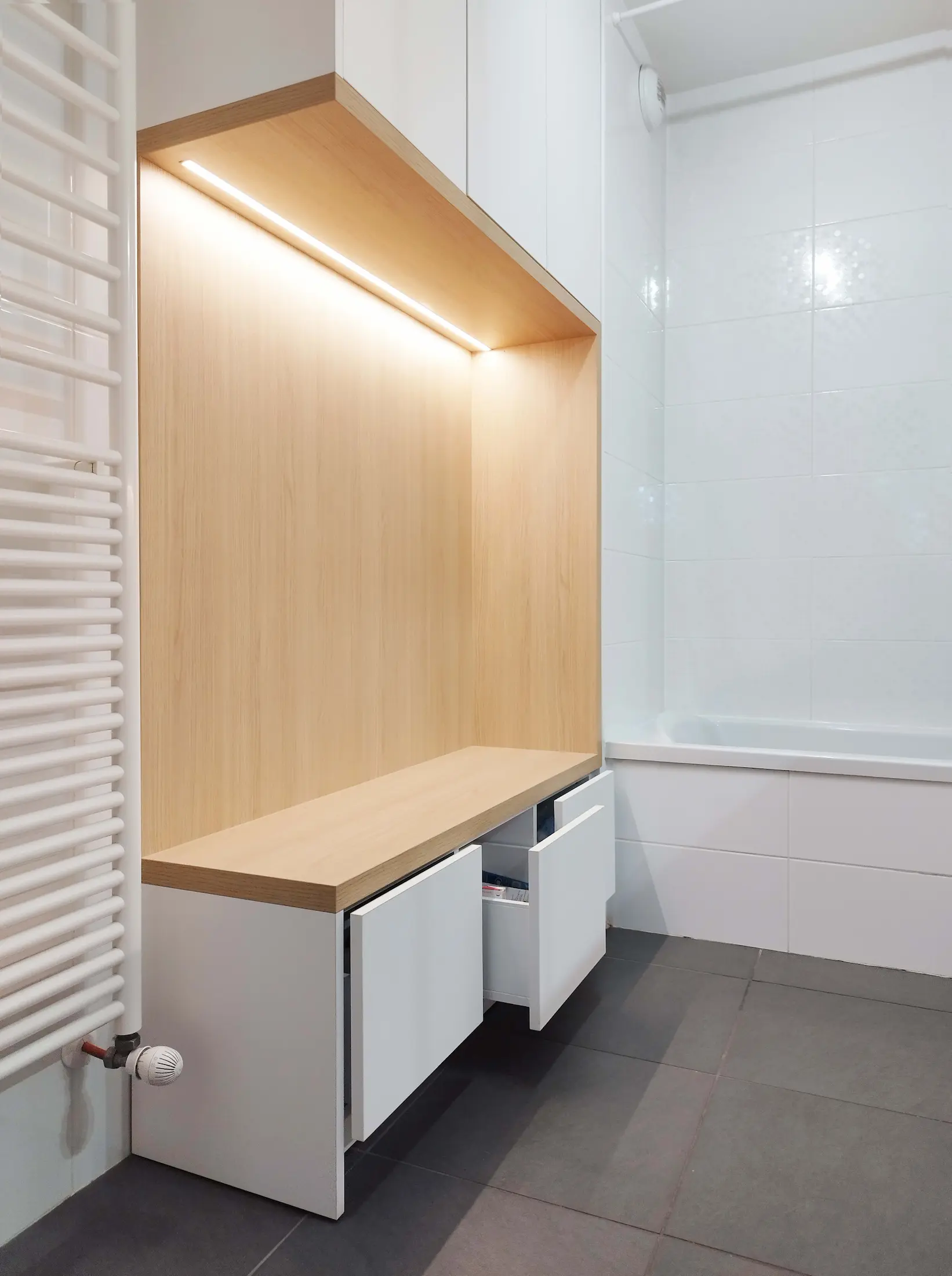 Niche de rangement en bois clair intégrée dans l’aménagement sur mesure réalisé par Jiwaa.