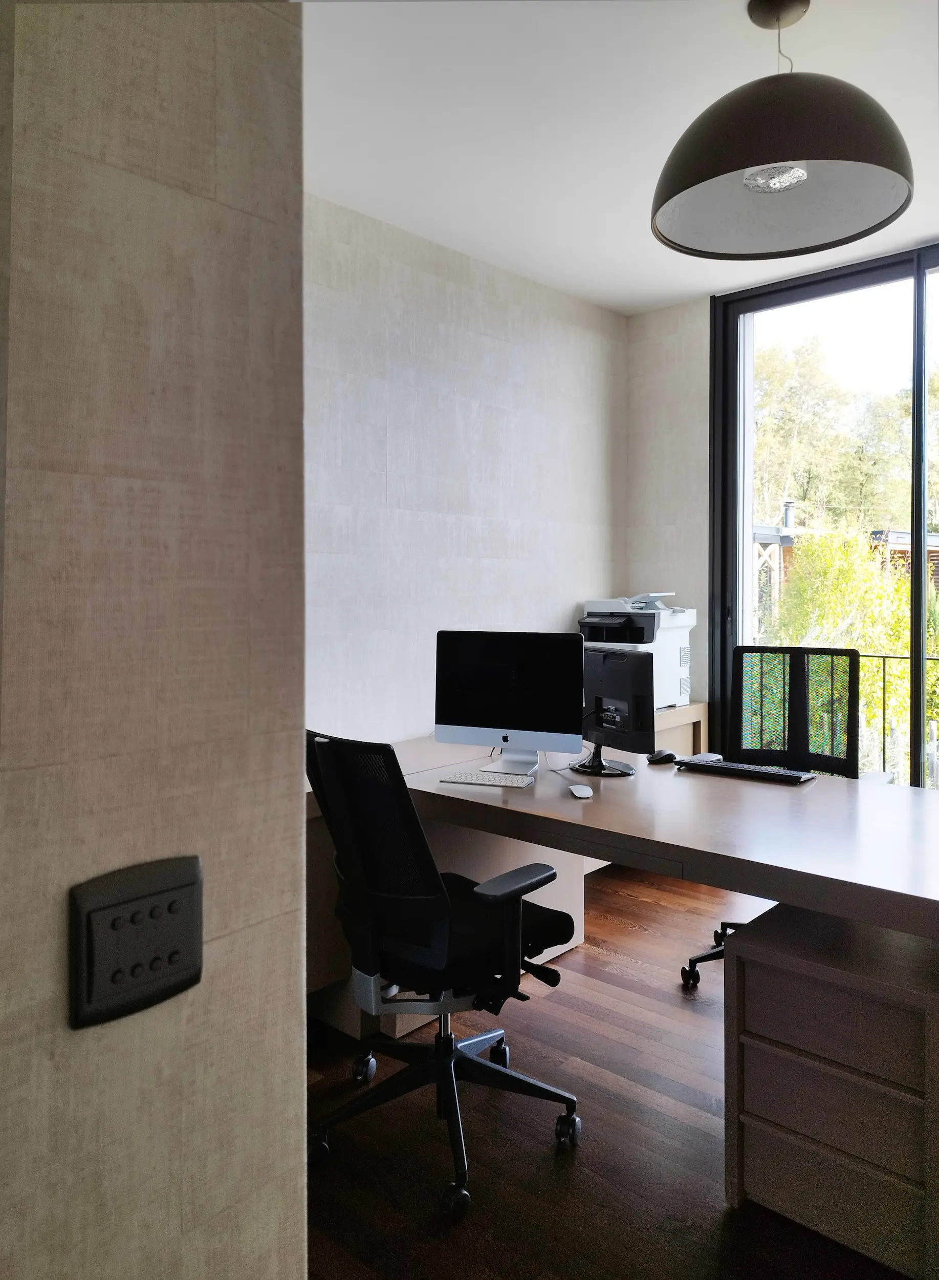 Bureau contemporain lumineux avec plan de travail clair et ouverture sur l’extérieur, dans une maison située dans l’Ouest lyonnais.