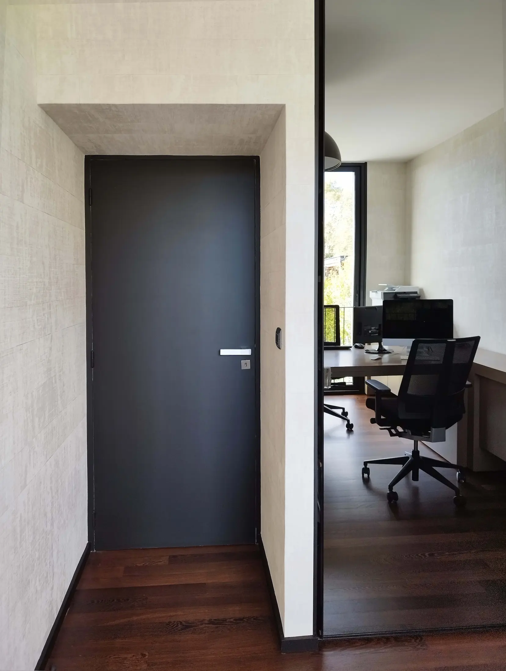 Accès au bureau avec porte sombre et murs clairs, contraste de matières dans une maison contemporaine rénovée.