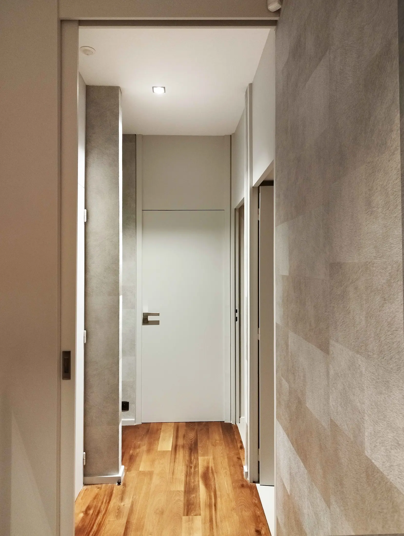 Vue du couloir intérieur rénové avec murs clairs et sol en bois, dans une maison de l’Ouest lyonnais.