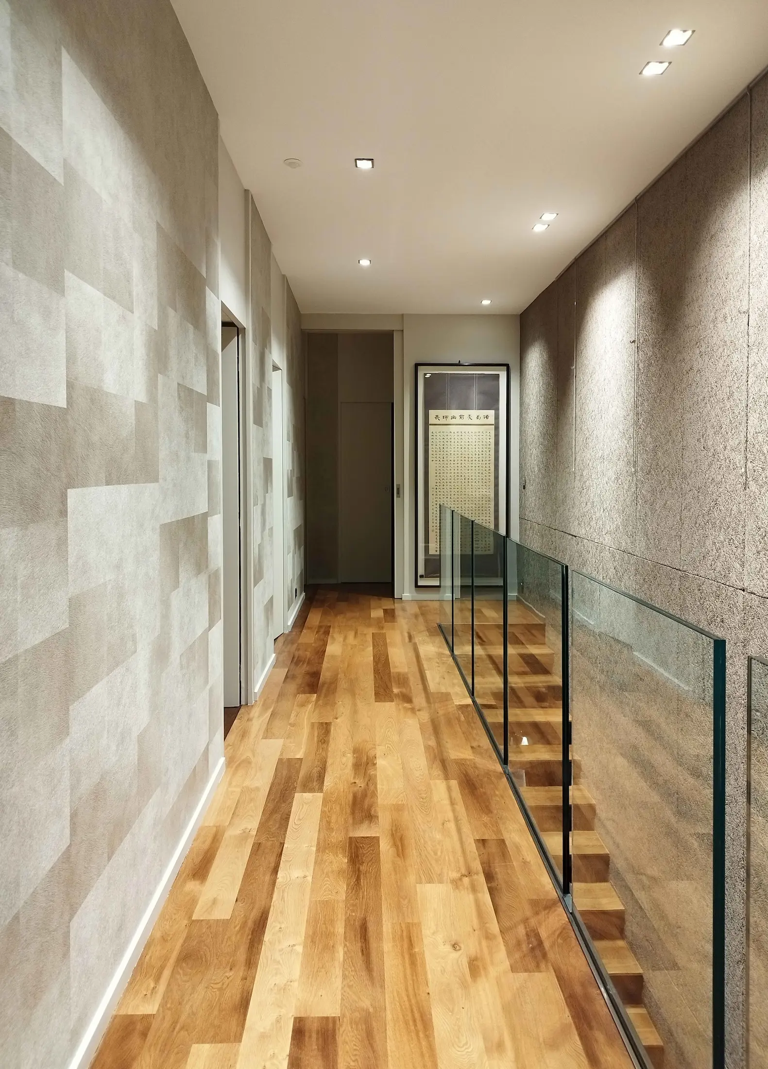 Couloir lumineux avec revêtements muraux clairs et éclairage discret, transformation d’un espace auparavant sombre.