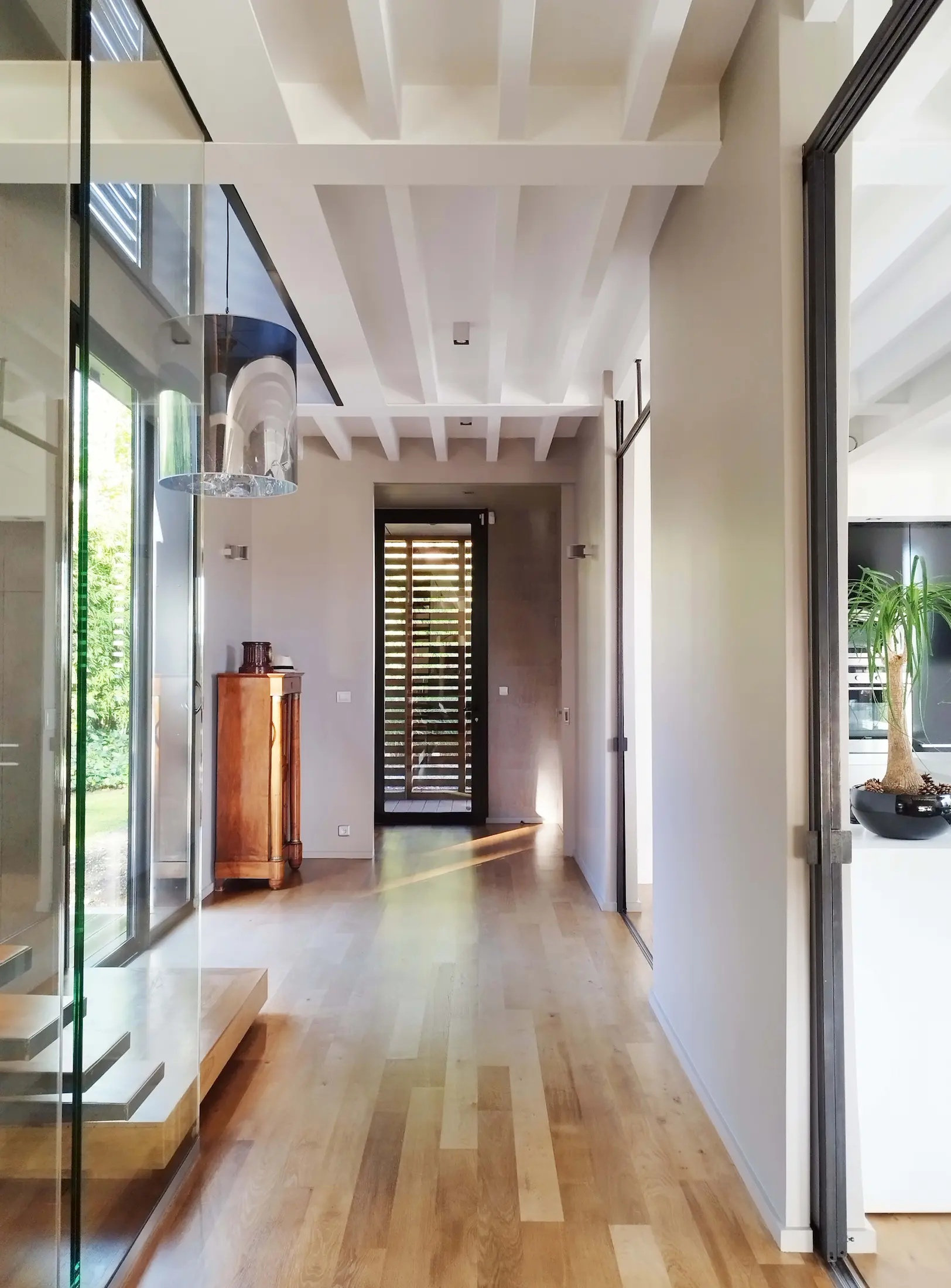 Entrée contemporaine lumineuse avec parquet en bois et volumes épurés.