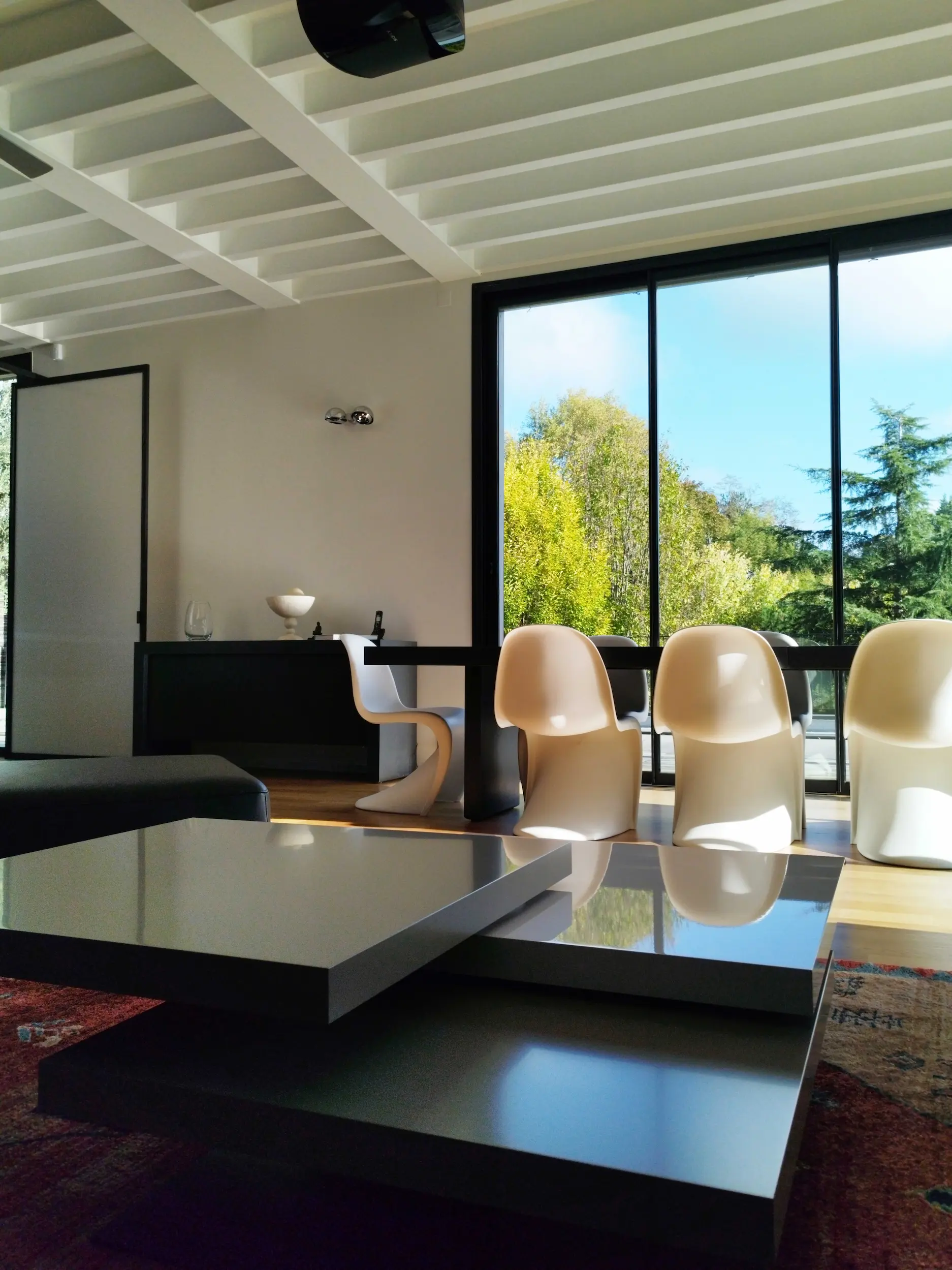 Salle à manger lumineuse avec mobilier contemporain et grandes ouvertures sur l’extérieur.