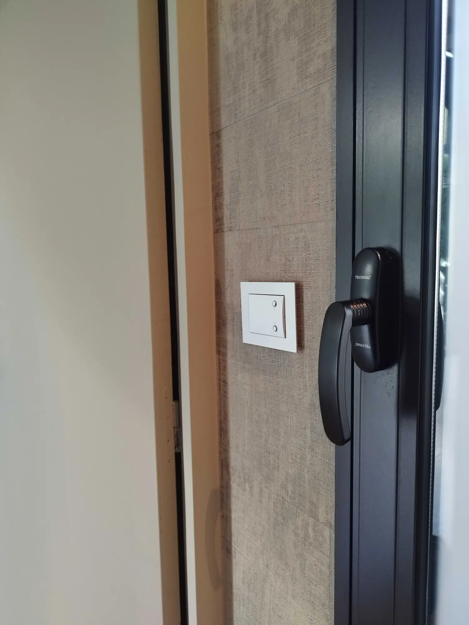 Détail de poignée et interrupteur dans un intérieur contemporain aux finitions soignées.