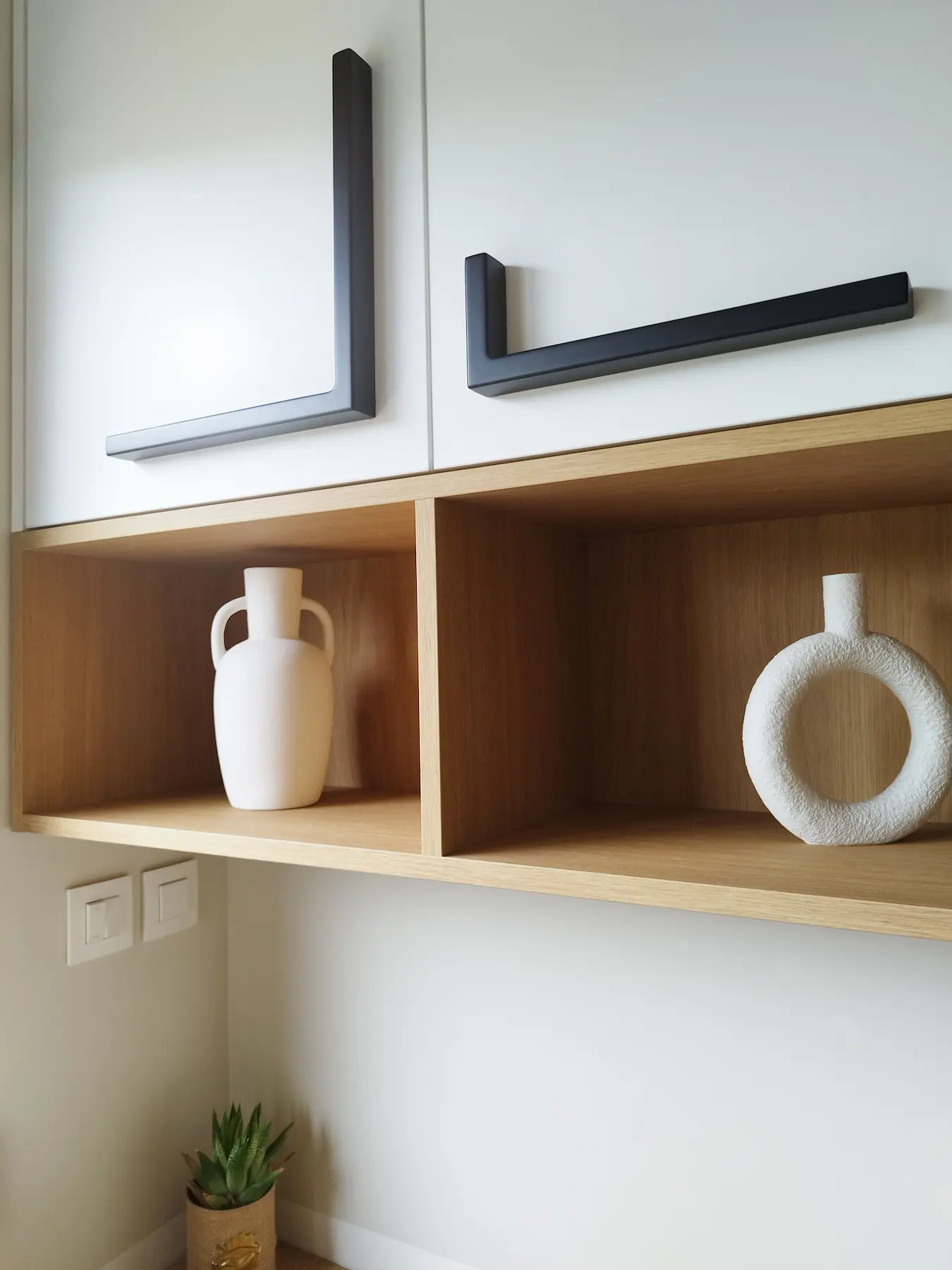 Détail des niches en bois et des rangements blancs, soulignant le travail des textures et des contrastes.