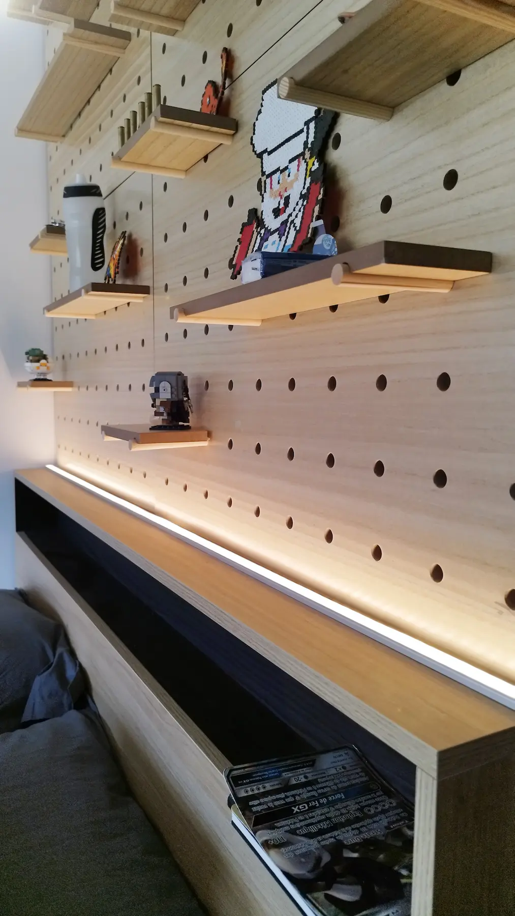 Plan rapproché du panneau perforé en bois et de ses étagères modulables, signature design du projet imaginé par Valentine Bourdier.