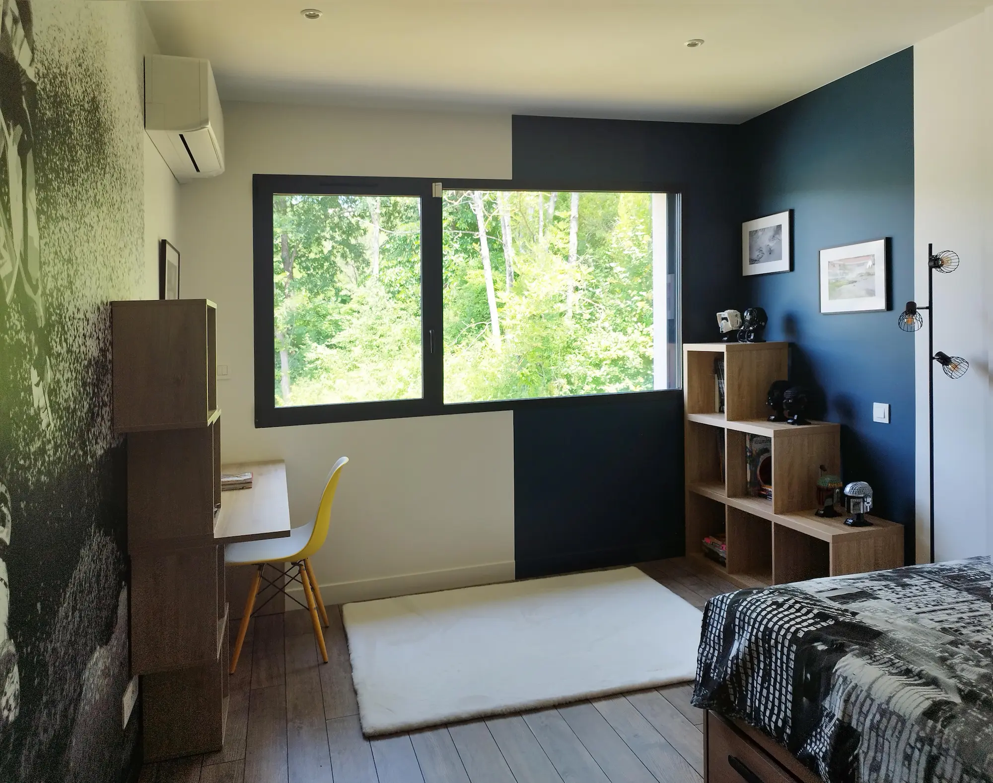 Chambre enfant baignée de lumière, mêlant bleu profond et vues sur la nature grâce à une large fenêtre.