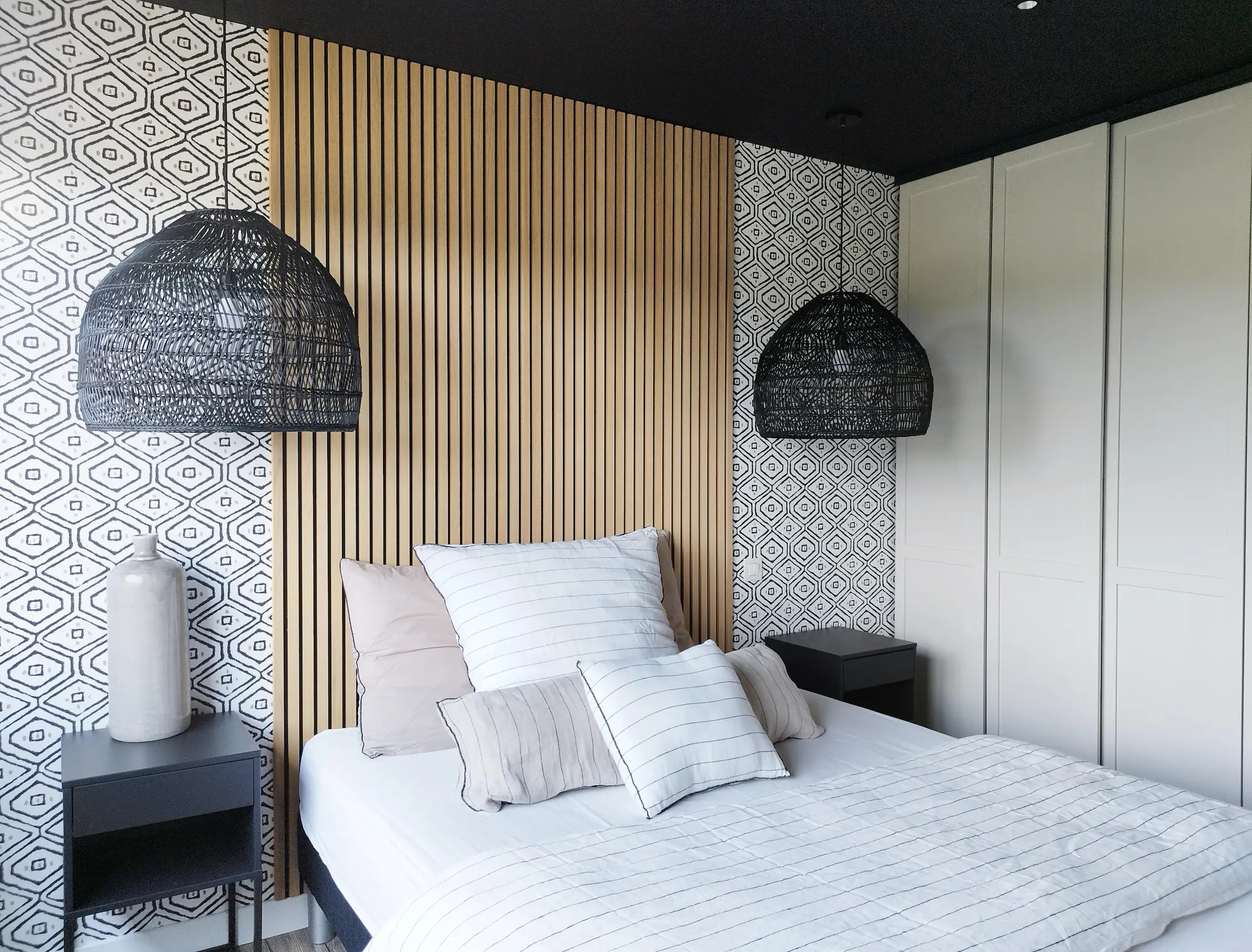 Tête de lit contemporaine animée par un jeu de tasseaux verticaux et de papier peint graphique, imaginé par l’agence Jiwaa.a.