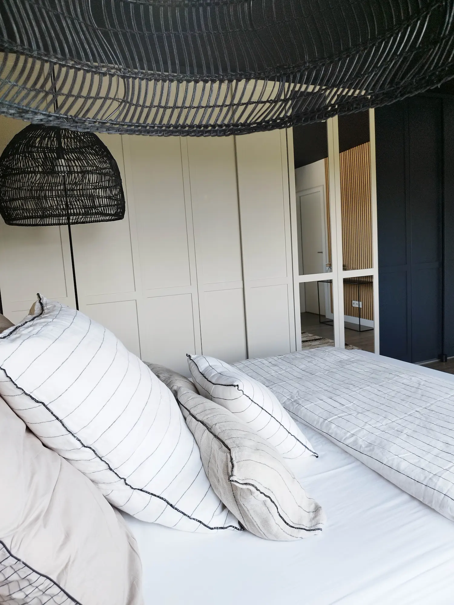 Perspective depuis le lit montrant les façades de placards beige clair contrastant avec un mur bleu nuit.