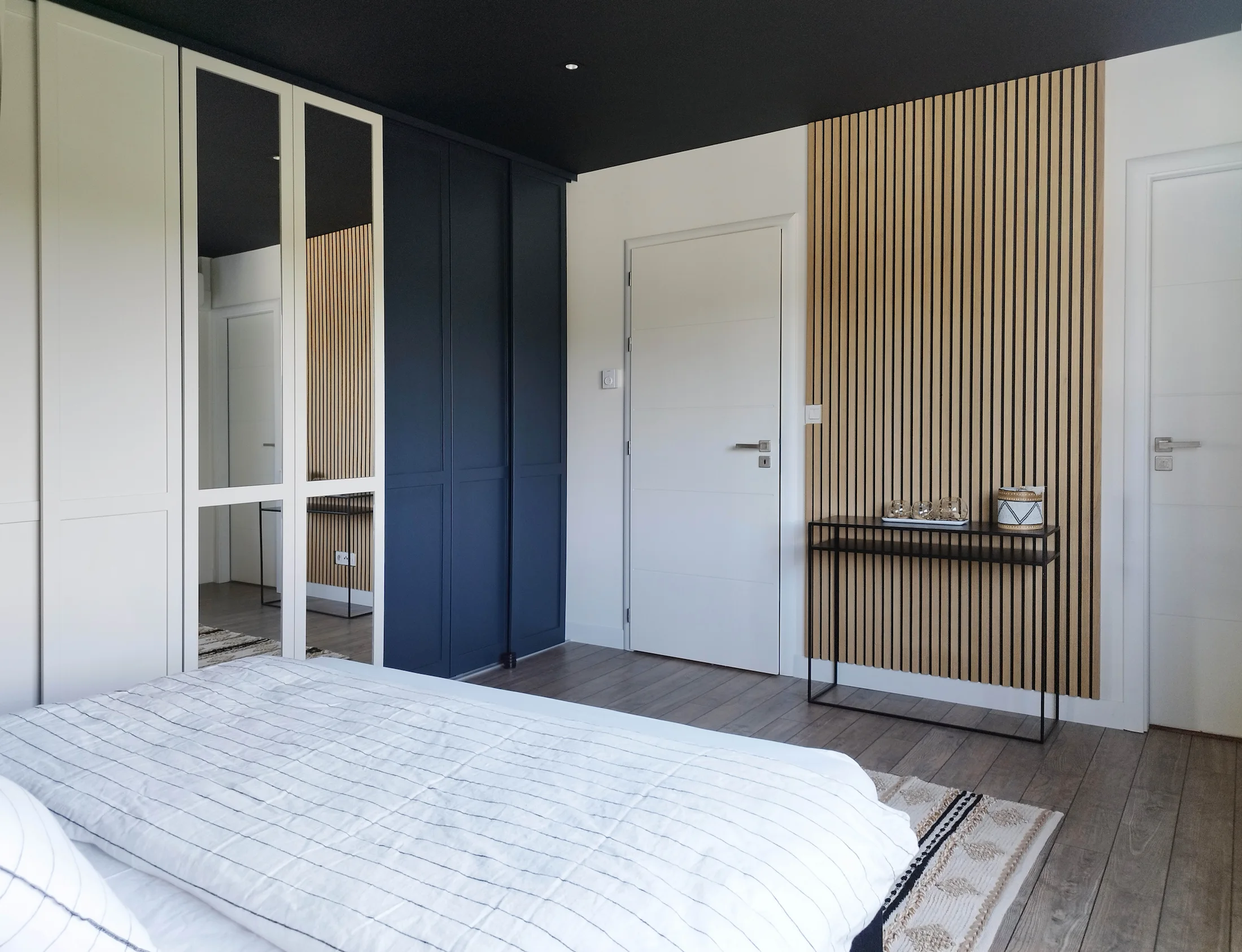 Vue large d’une chambre parentale où les tasseaux de bois deviennent un accent mural élégant face au lit.