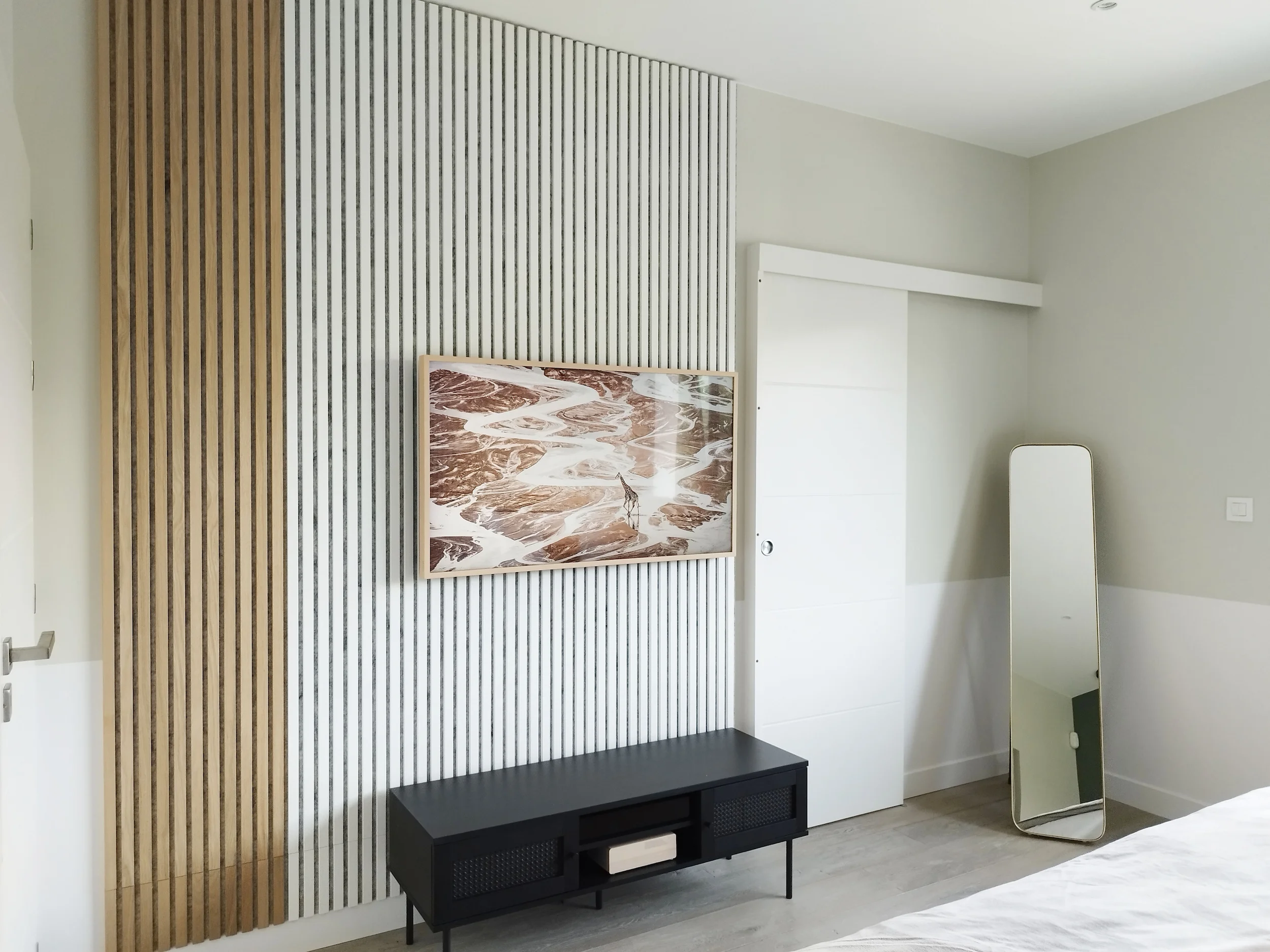 Mur TV décoratif associant tasseaux bois clairs et panneaux texturés blancs pour un rendu contemporain.