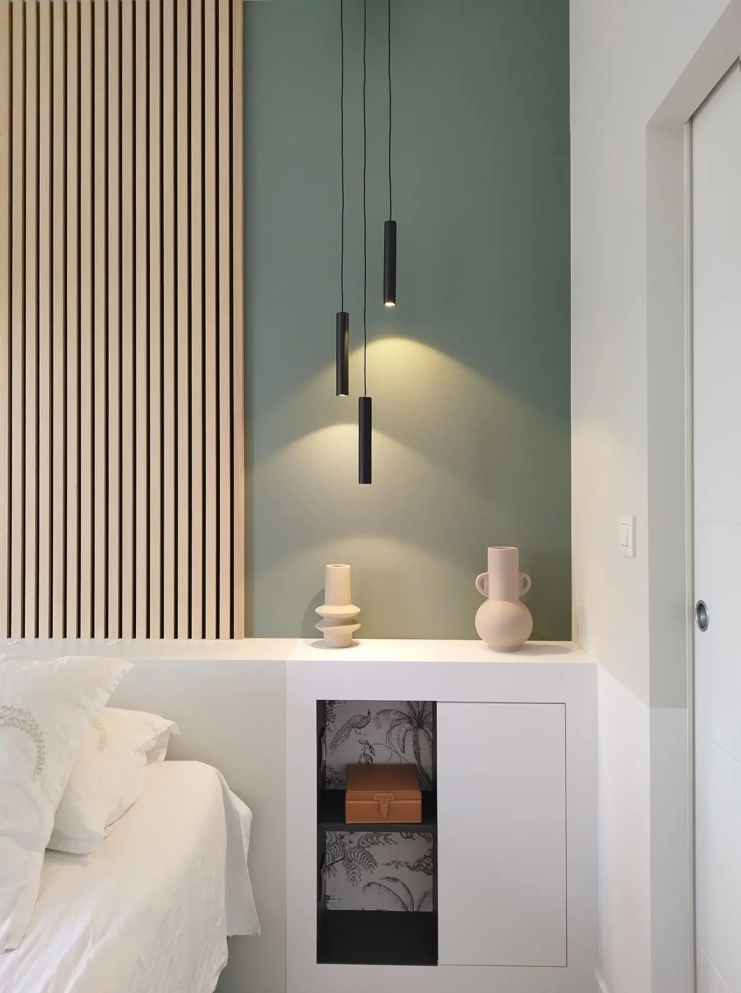 Chevet intégré avec niche décorative et éléments en céramique, éclairé par des suspensions minimalistes.