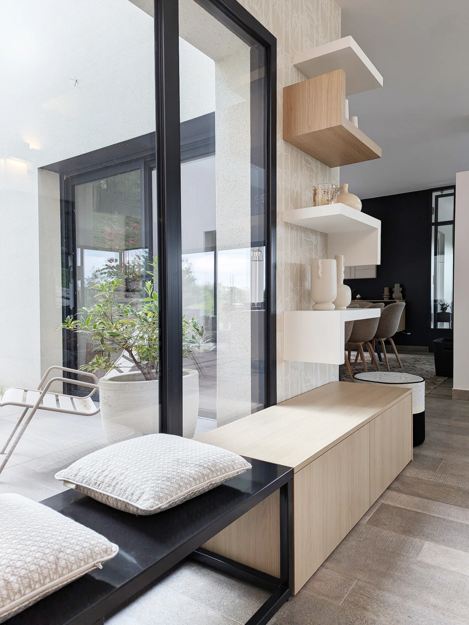 Espace d’entrée avec banc en bois clair et étagères graphiques alternant formes blanches et bois.