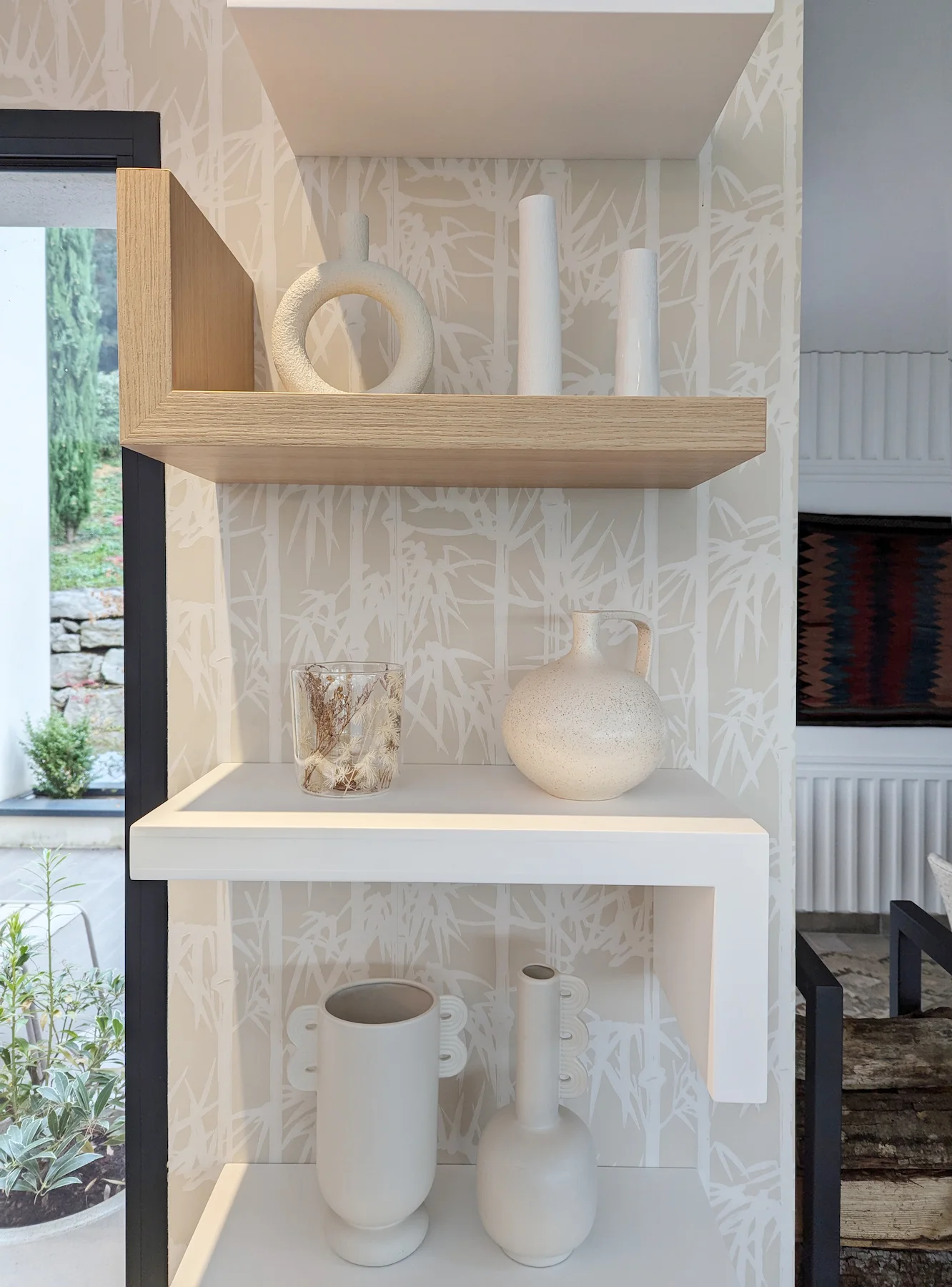 Zoom sur les étagères murales décorées d’objets en céramique dans un coin lumineux de la pièce.