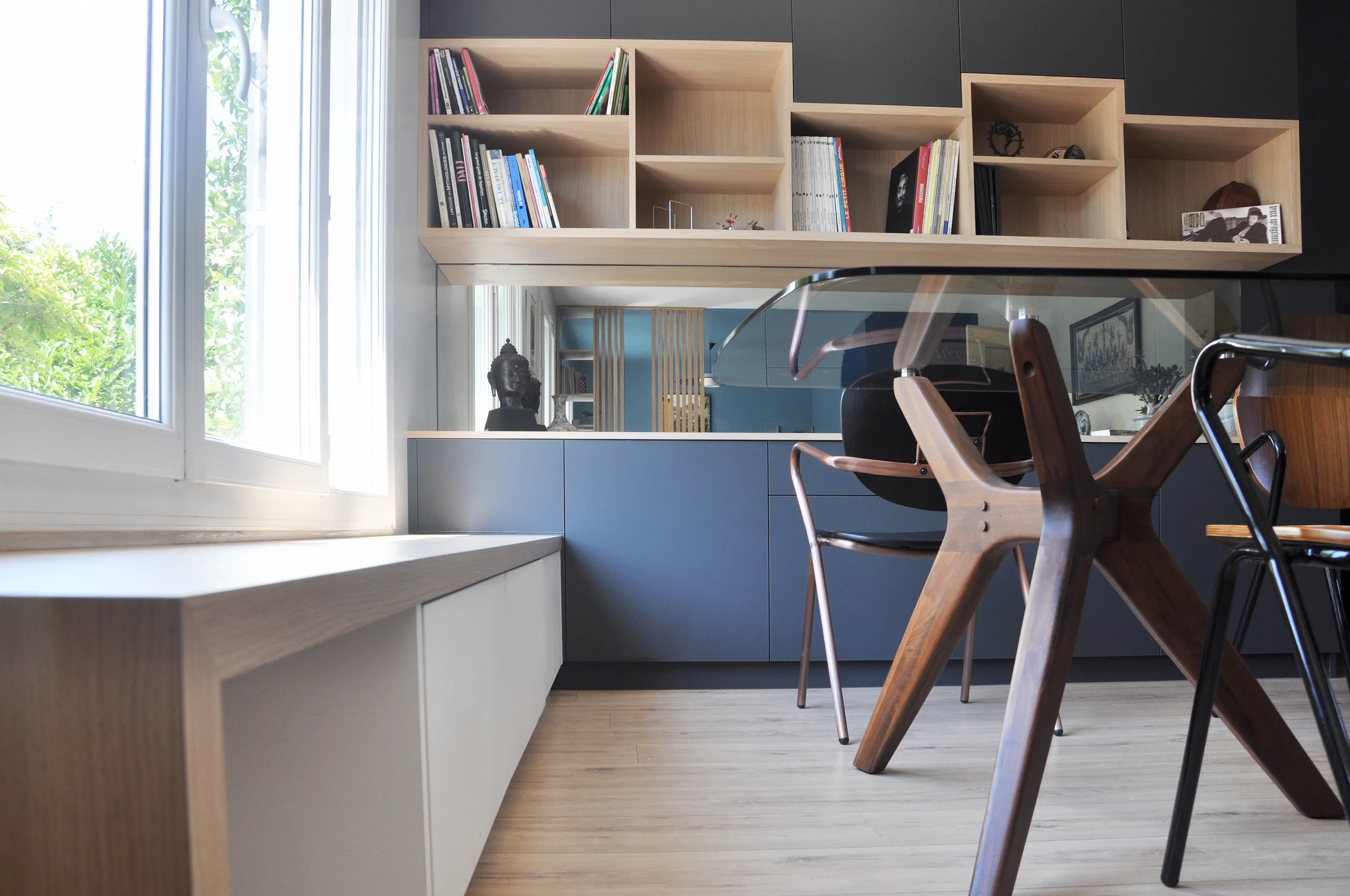 Bibliothèque sur mesure en bois clair et meuble bas, optimisant la pièce de vie autour de la lumière naturelle.