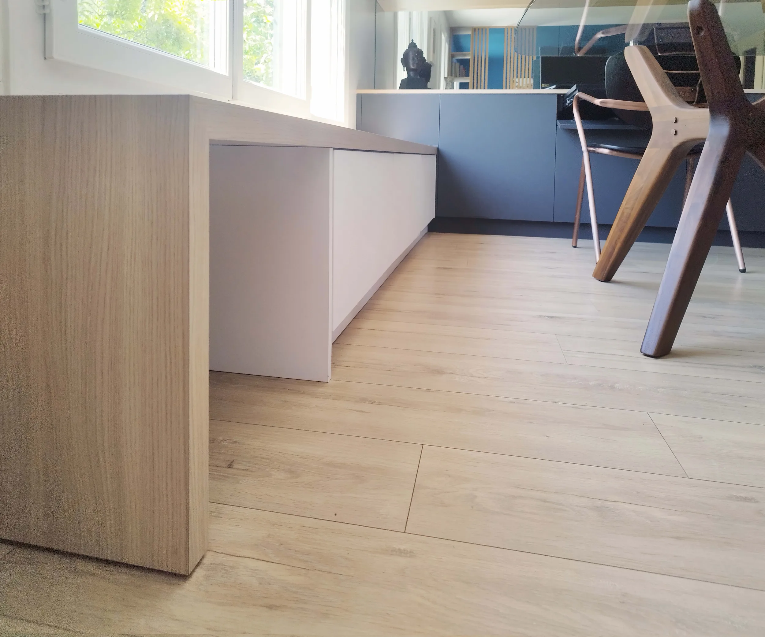 Détail du meuble bas en bois clair, intégré à l’aménagement sur mesure.