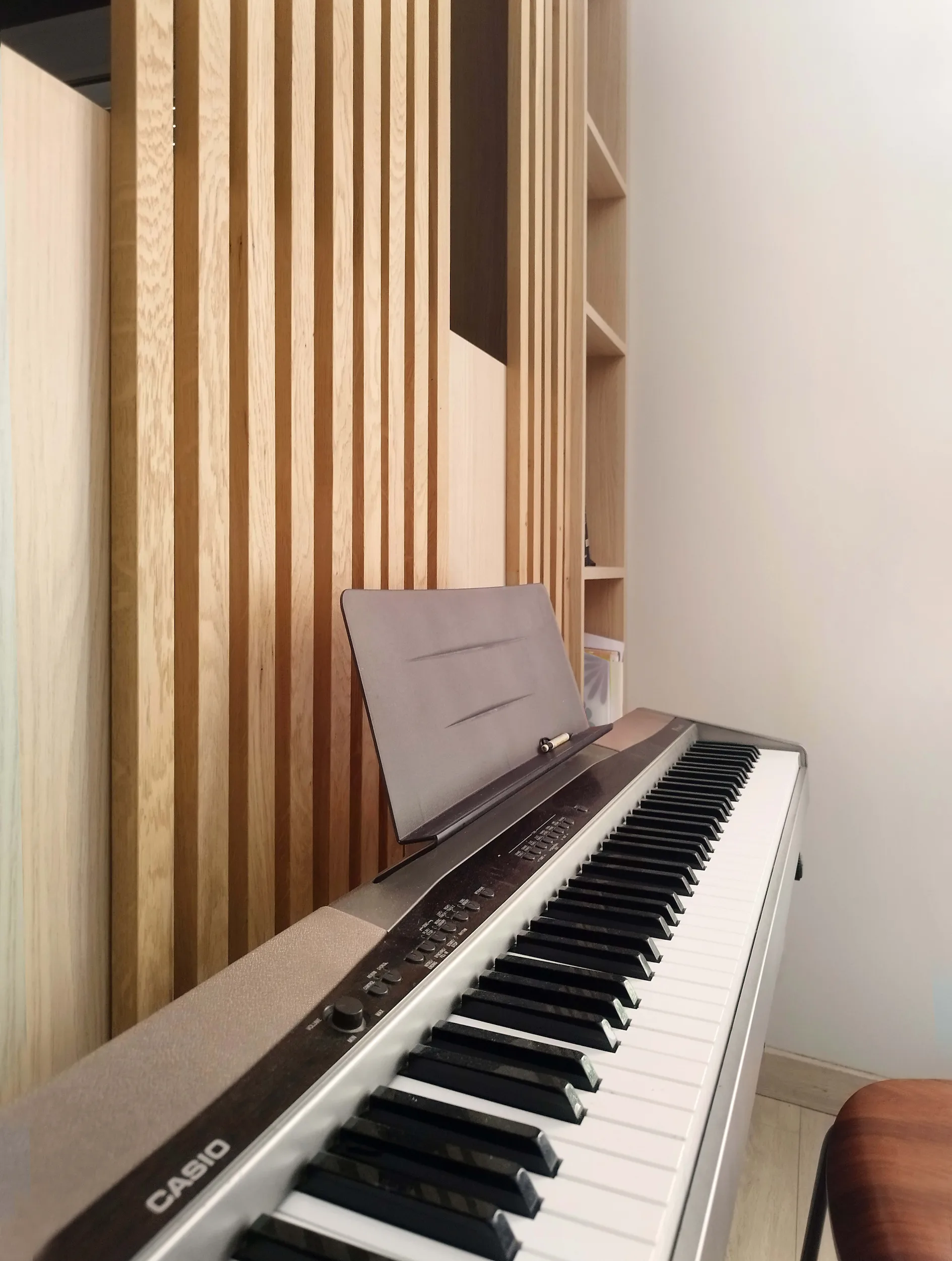 Claustra en bois et piano intégrés dans un espace de vie repensé.