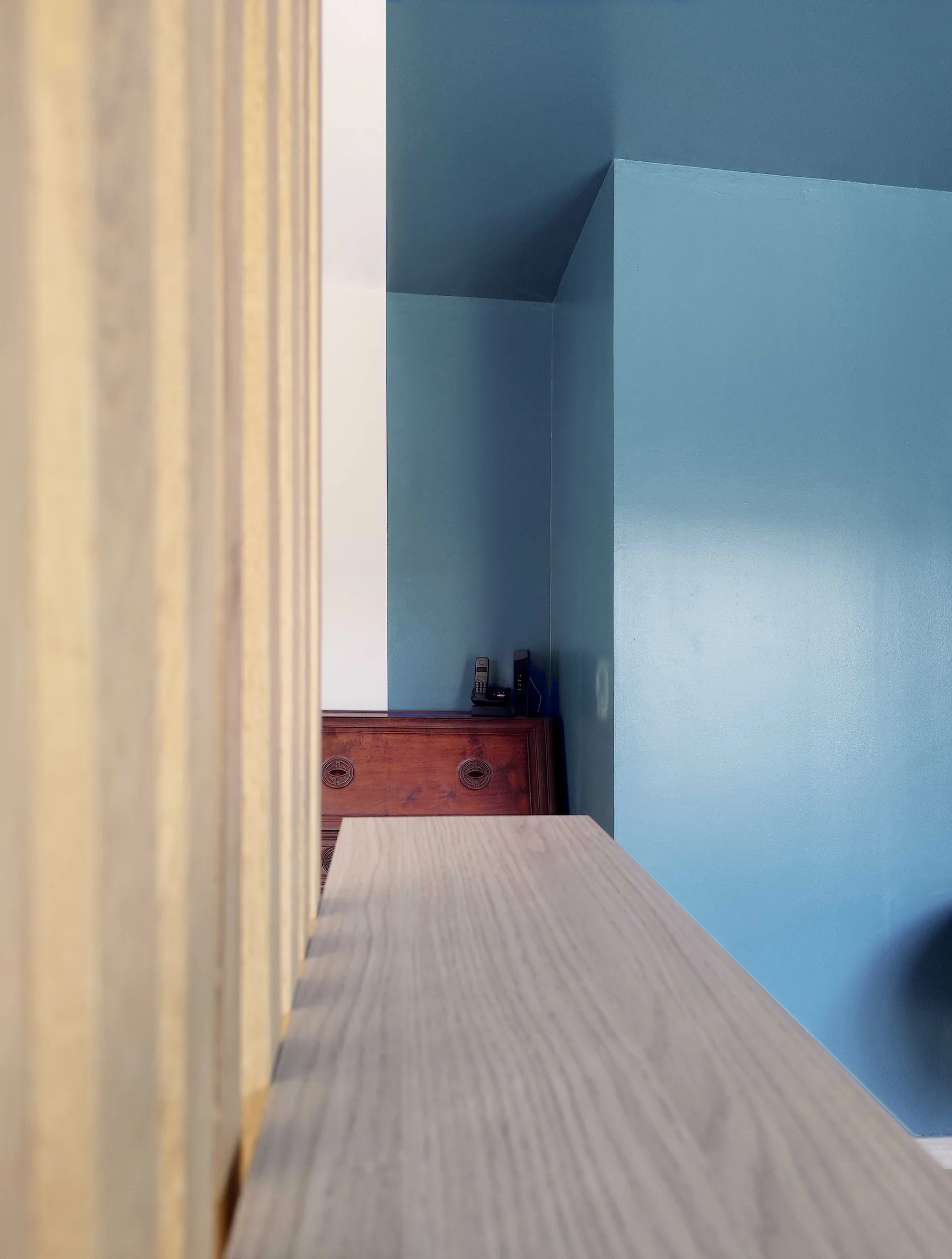 Claustra bois et meuble sur mesure structurant l’espace de vie, avec peinture bleue et rangements intégrés.