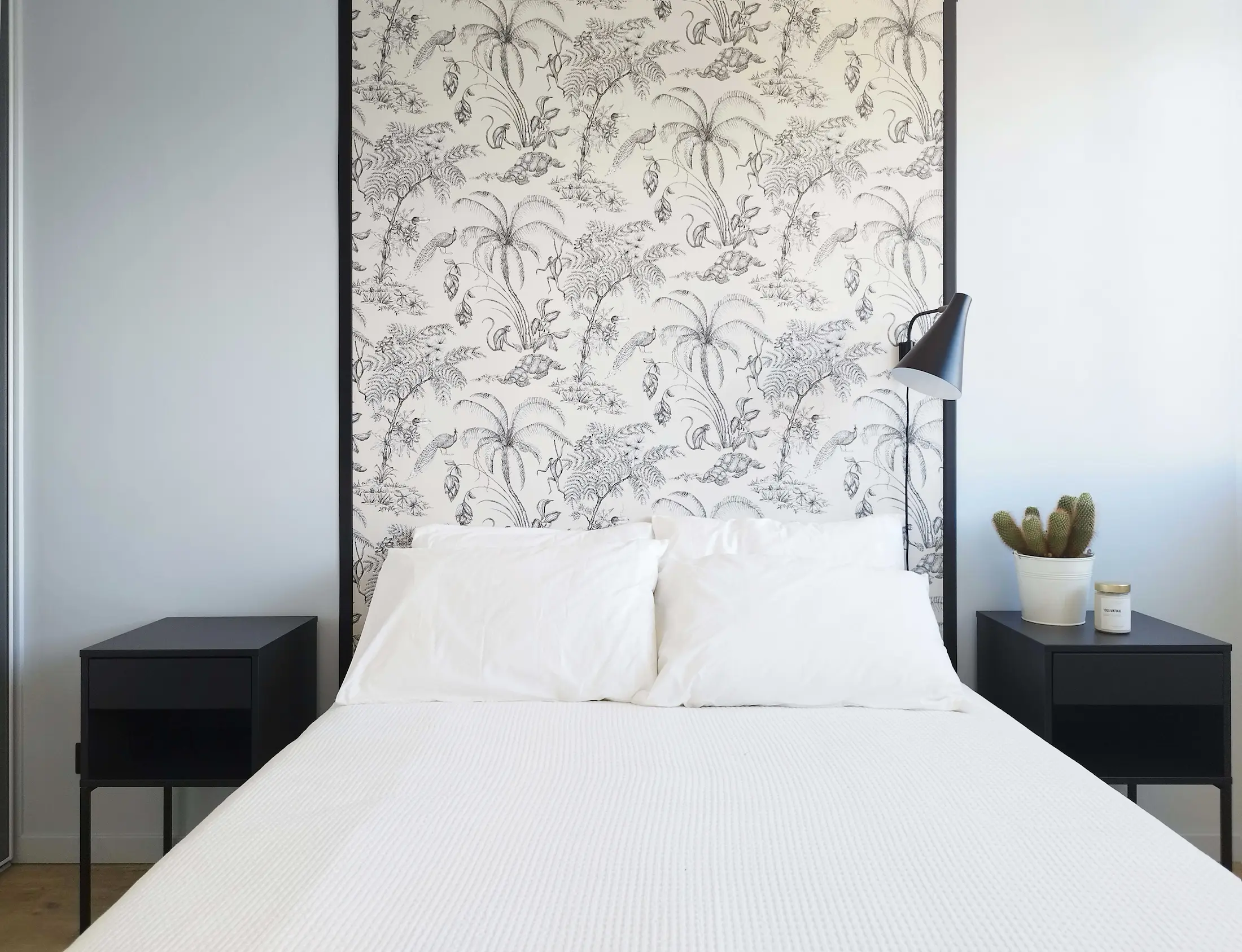 Chambre lumineuse rénovée avec une tête de lit en papier peint botanique noir et blanc et mobilier minimaliste.