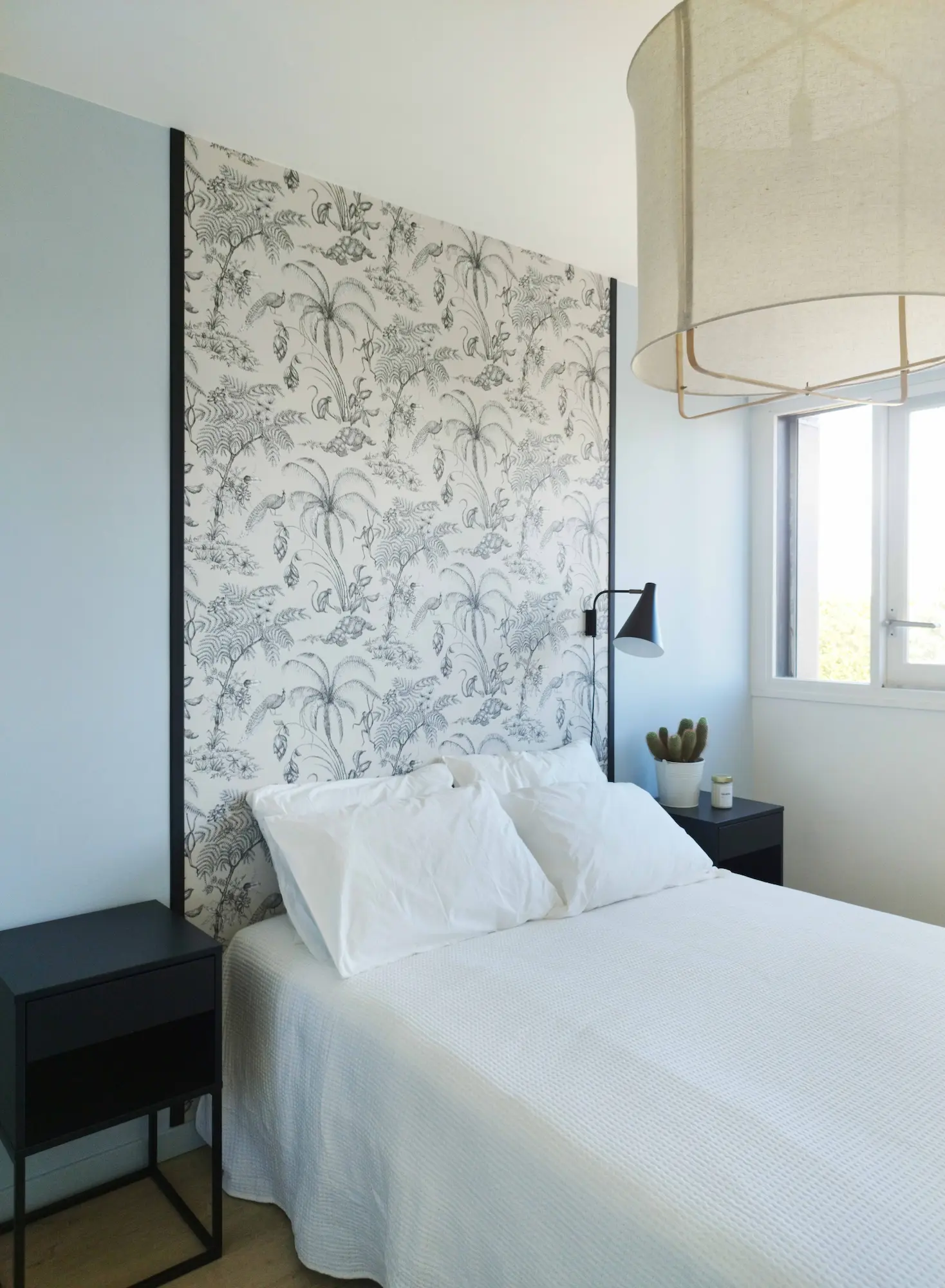 Espace nuit d’un appartement restructuré, mêlant papier peint, teintes douces et lumière naturelle.