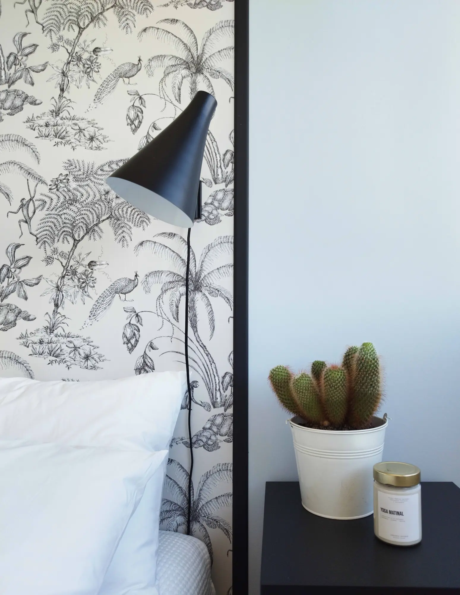 Détail décoratif d’une chambre rénovée : applique noire contemporaine et cactus sur table de nuit. Réalisation Valentine Bourdier architecte d’intérieur.