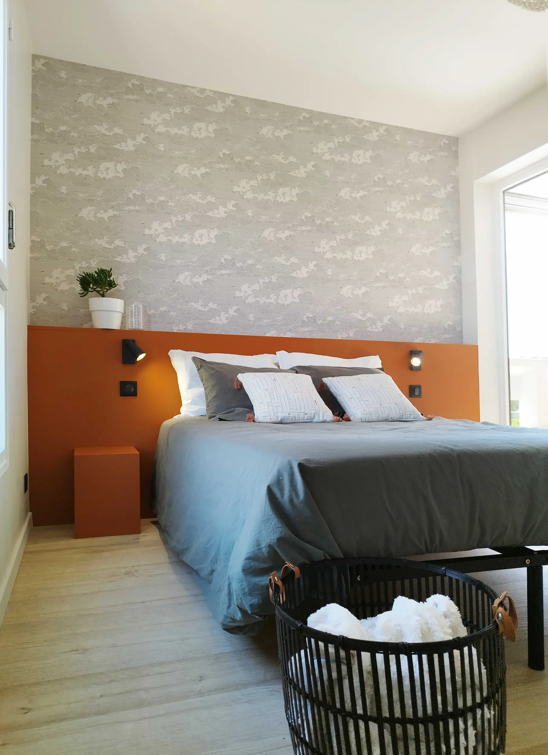 Vue d’ensemble de la chambre principale rénovée avec tête de lit terracotta, papier peint texturé et mobilier minimaliste, un projet signé Valentine Bourdier.