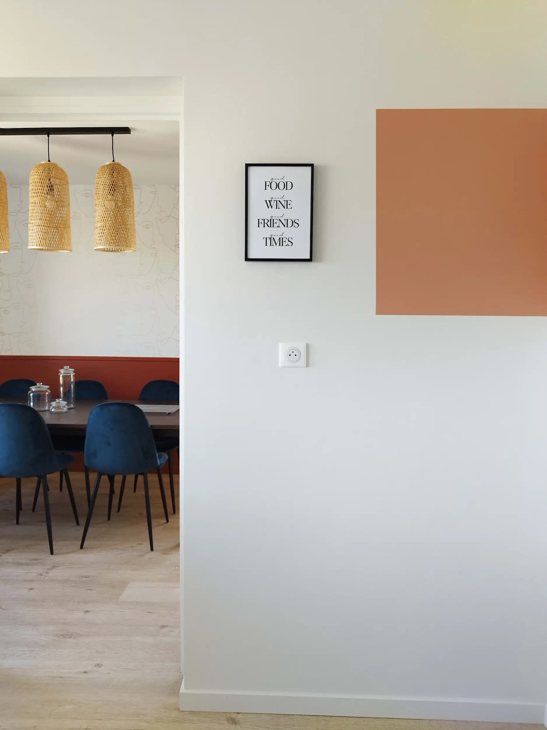 Vue vers la salle à manger avec suspensions en fibres naturelles et mur coloré, ambiance douce et chaleureuse.