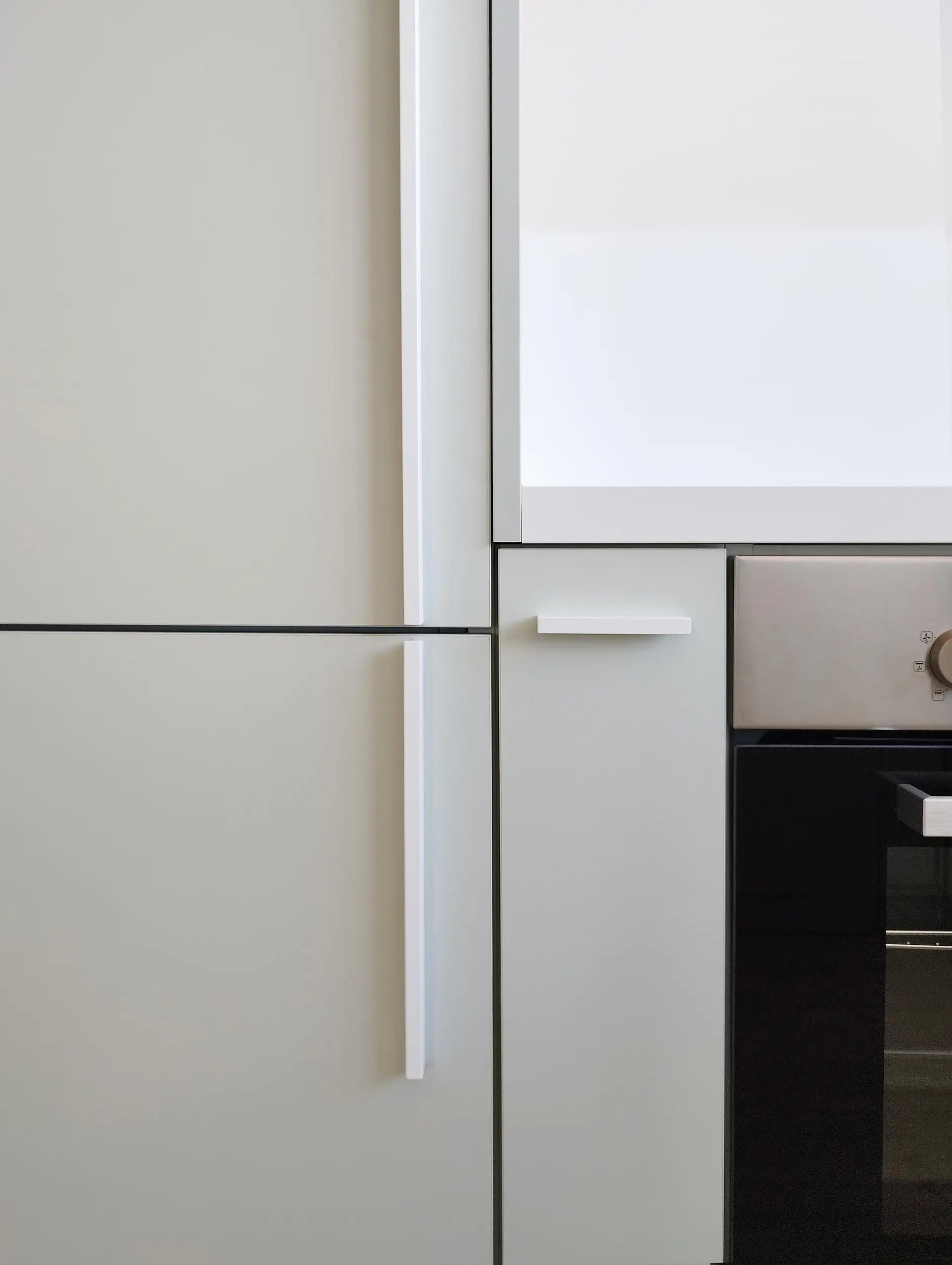 Détail des poignées minimalistes blanches intégrées aux façades de cuisine, reflet du design harmonieux pensé par l’agence Jiwa.a.